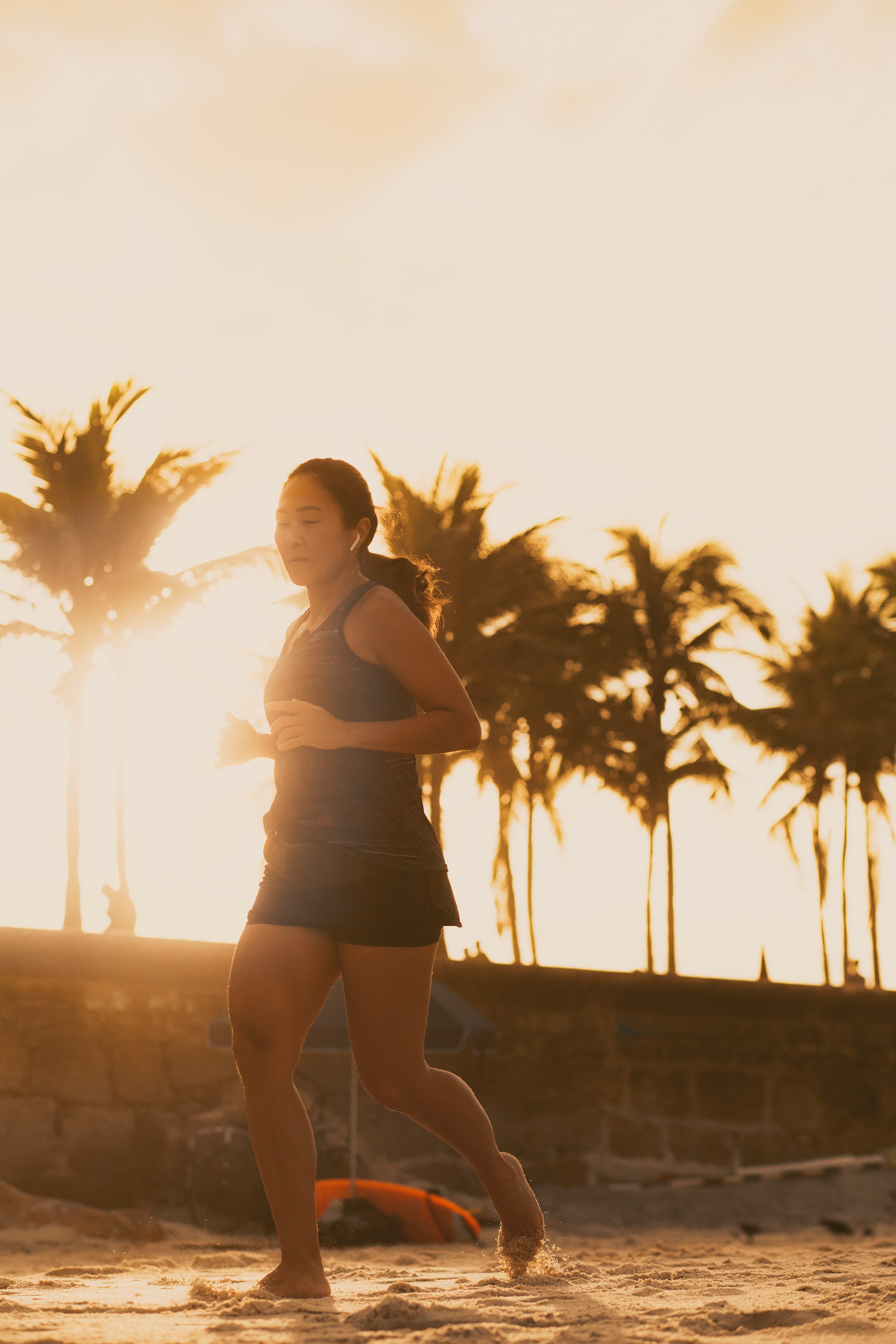 Un coureur étirant ses jambes sur une piste d'athlétisme au lever du soleil, se concentrant sur sa récupération.