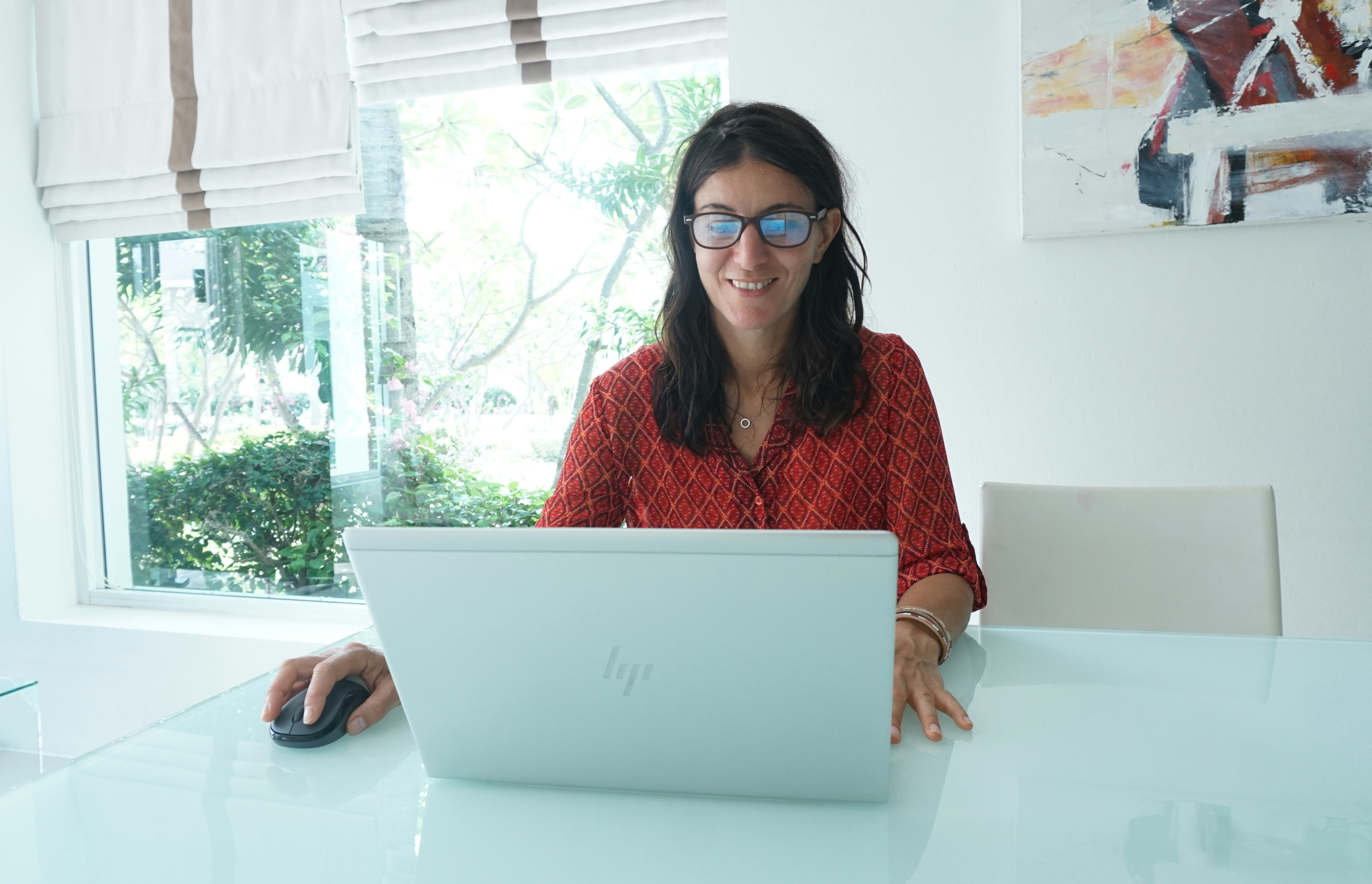 Une femme d'affaires assise à son bureau, souriante et concentrée, travaillant sur un ordinateur portable, avec des documents bien organisés à côté d'elle.