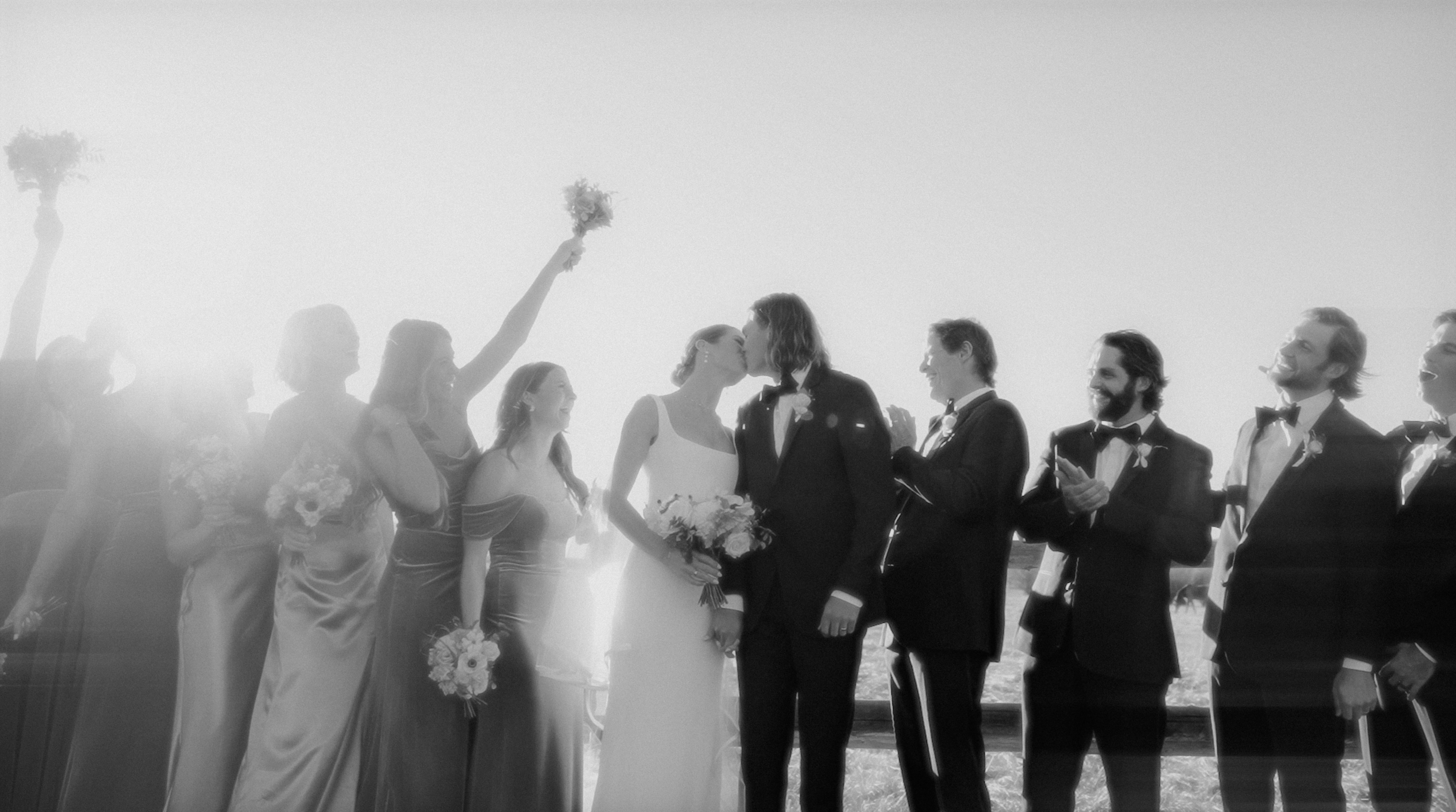 Invités de mariage riant de bon cœur lors d'un discours, capturés dans un moment spontané et joyeux.