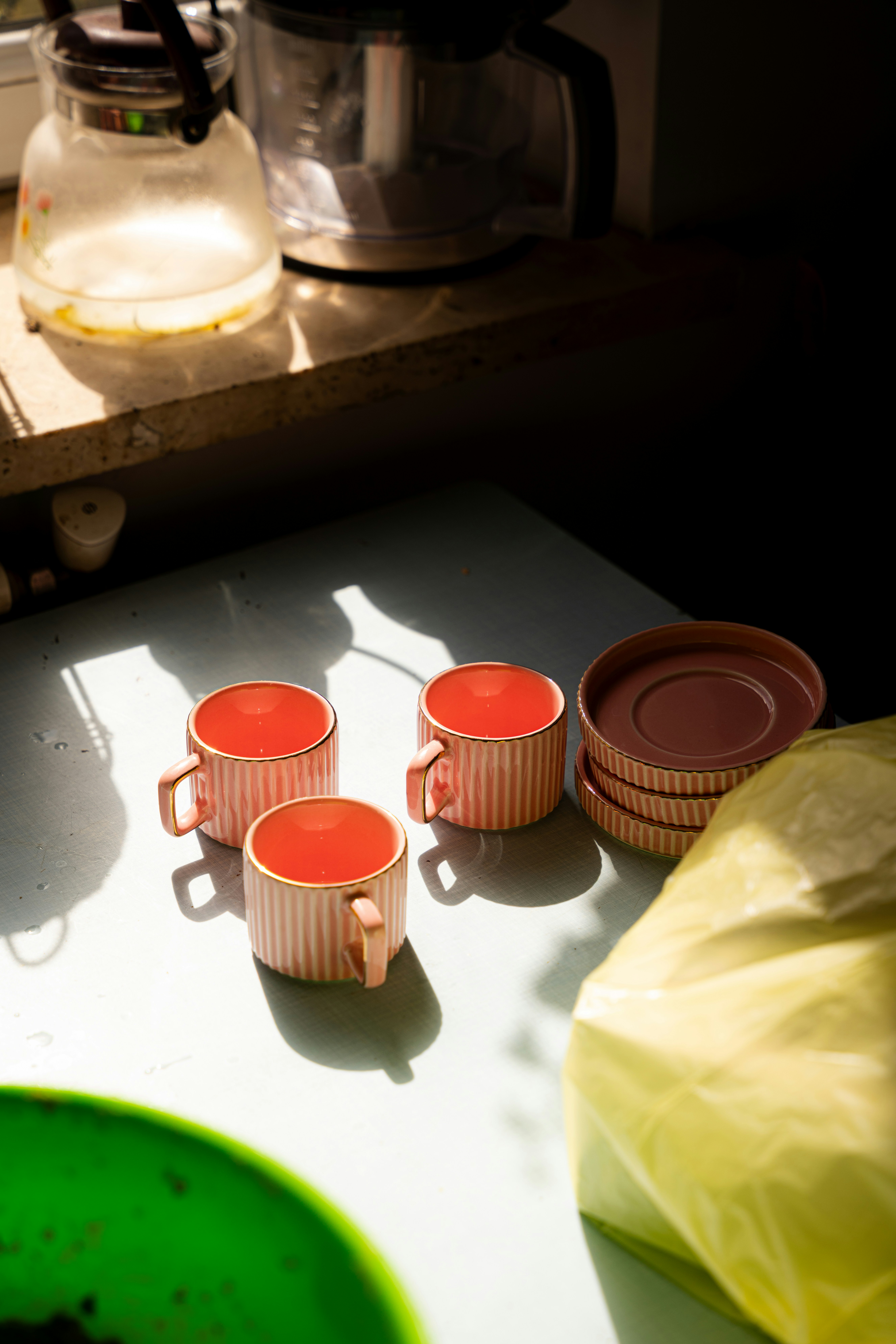 Une étagère en bois où s'alignent des mugs en céramique colorée et de petites assiettes aux motifs peints à la main.