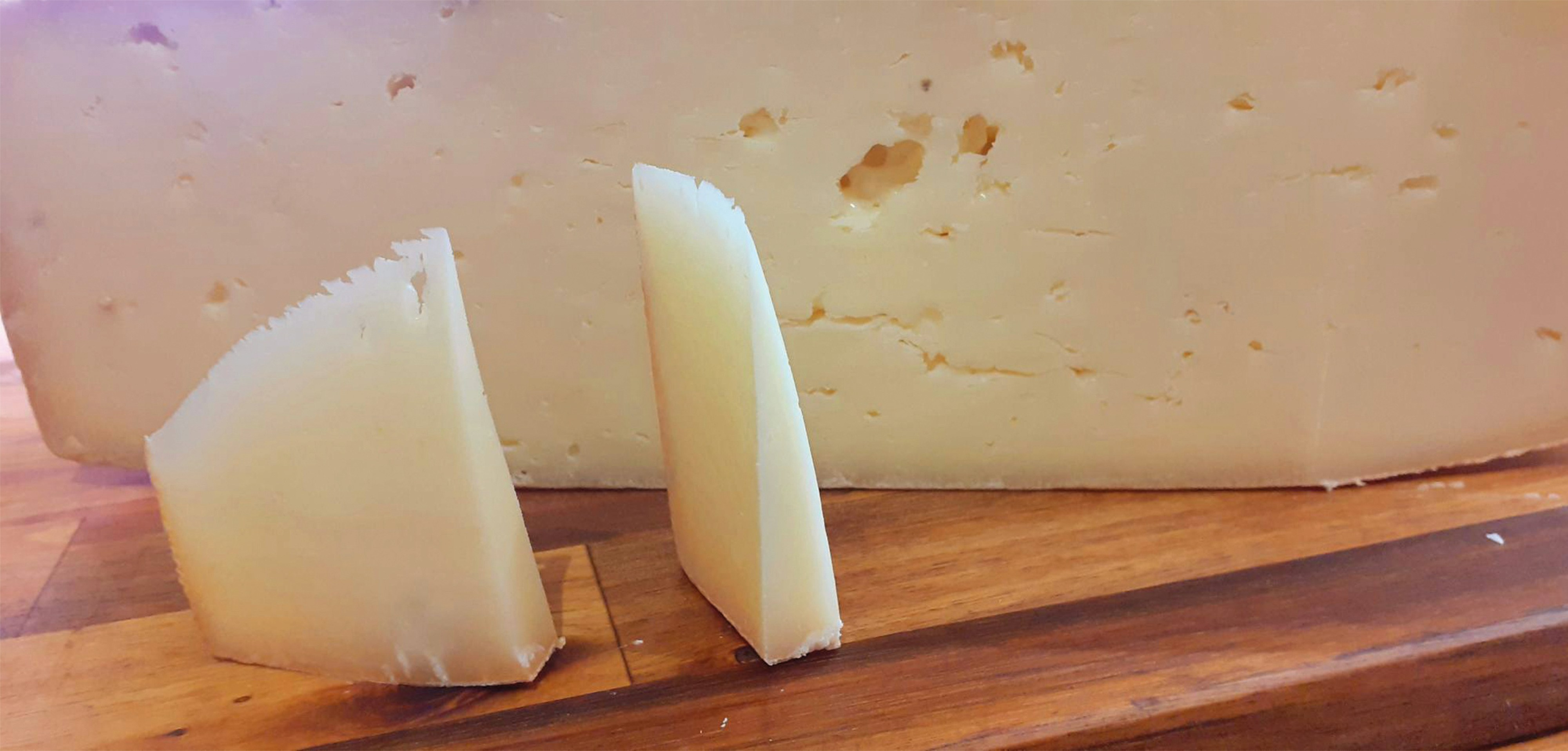 Une sélection de fromages suisses, dont du Gruyère, de l'Emmental et du Tilsiter, joliment disposée sur une planche en bois rustique avec quelques grappes de raisin.