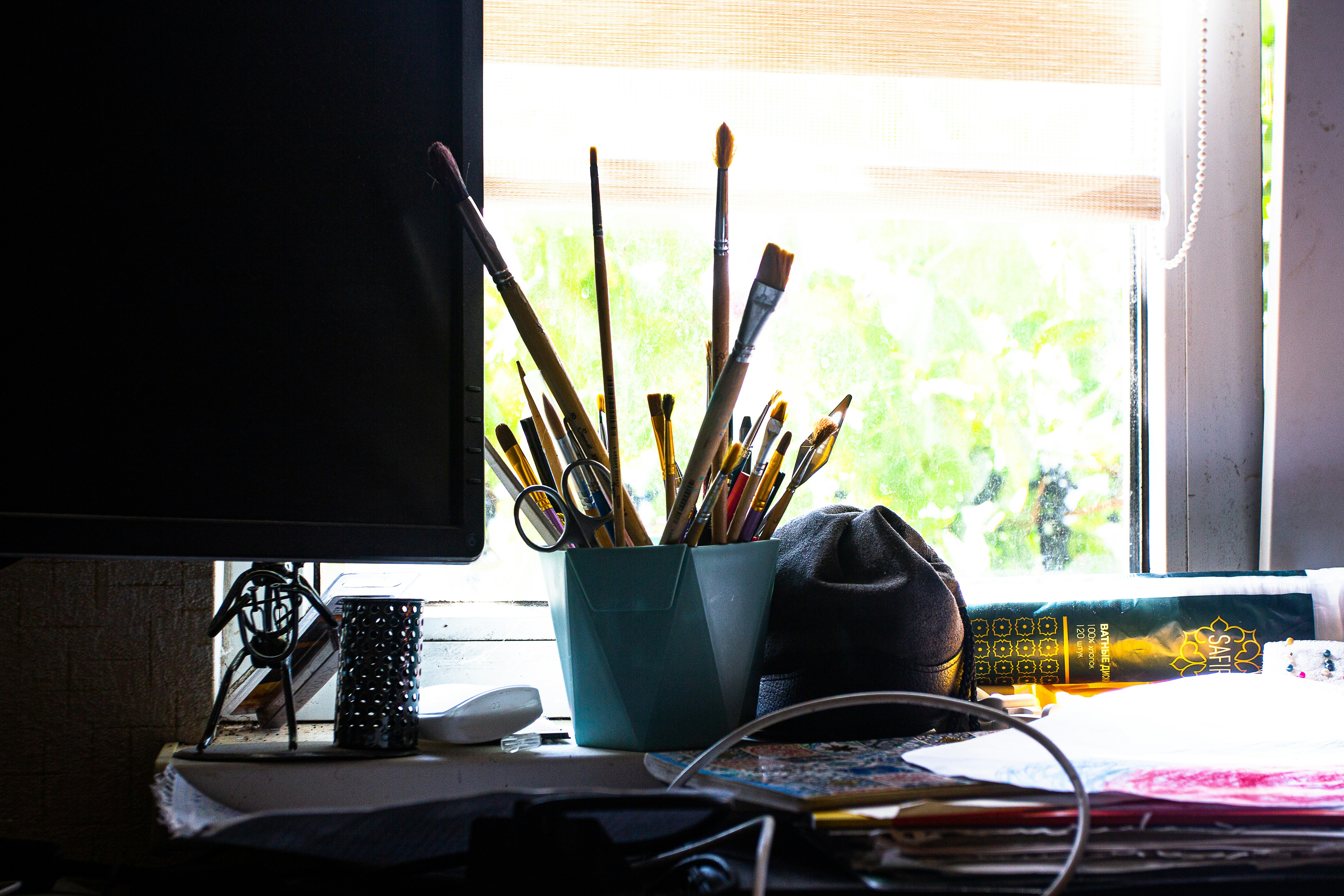 An artist's studio with paint brushes, canvases, and a laptop open on a desk. The mood is creative and focused.