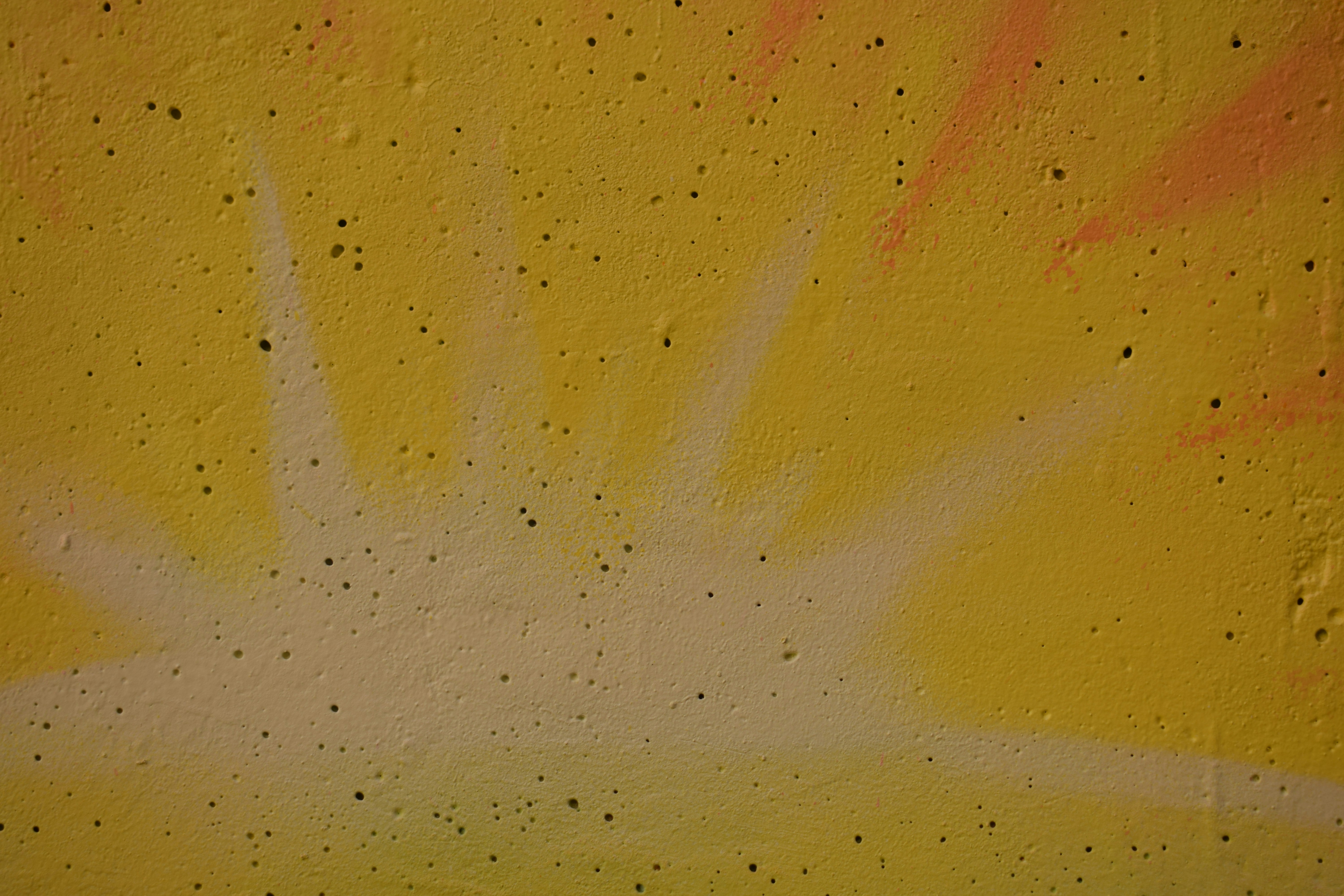 Des pots de peinture de différentes couleurs et des pinceaux de haute qualité posés sur une bâche de protection, prêts pour un projet de ravalement de façade.