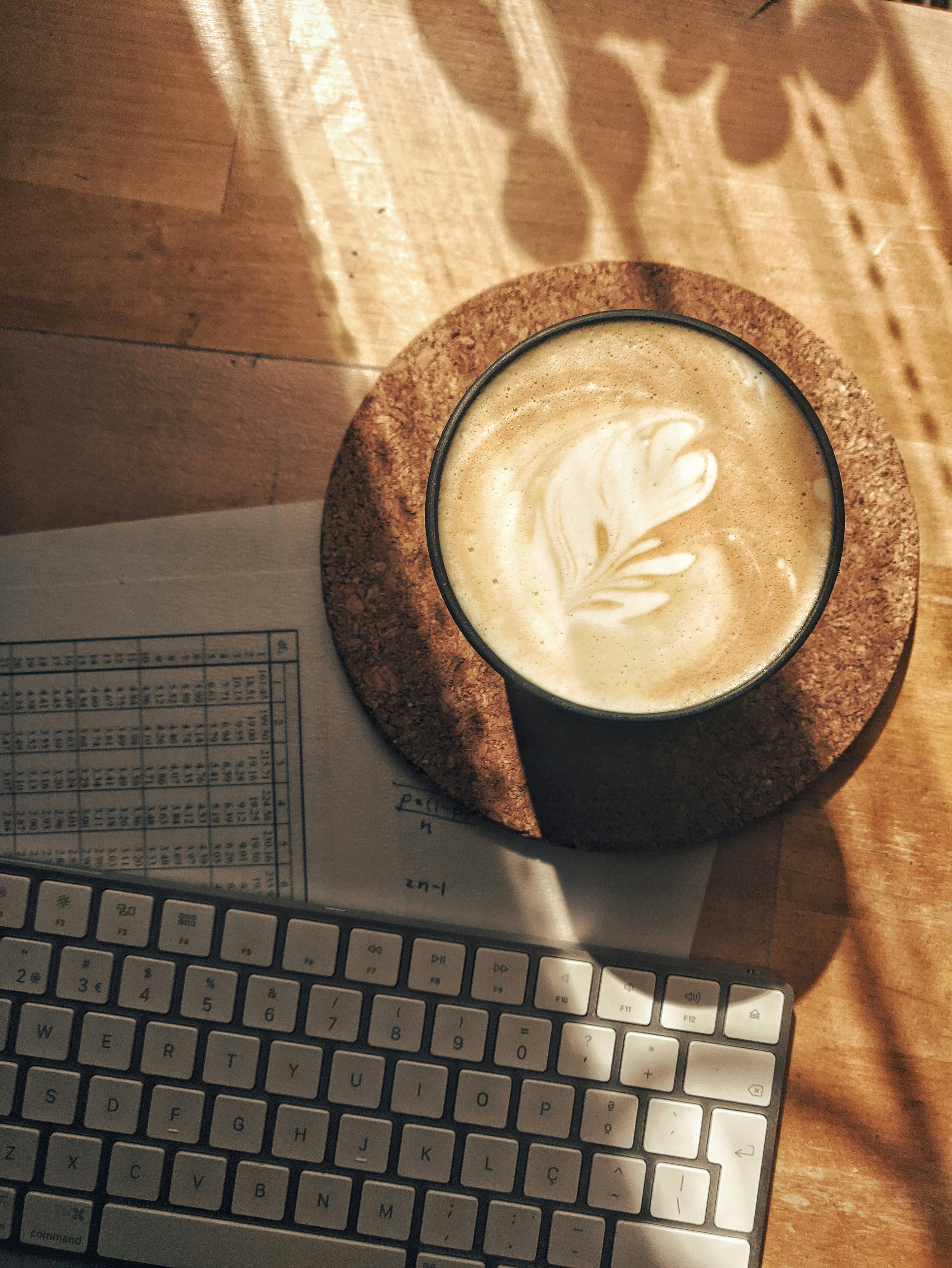 A shot of someone at a wooden desk, focused on their laptop screen as they carefully review and edit text, with a coffee mug ready for action.