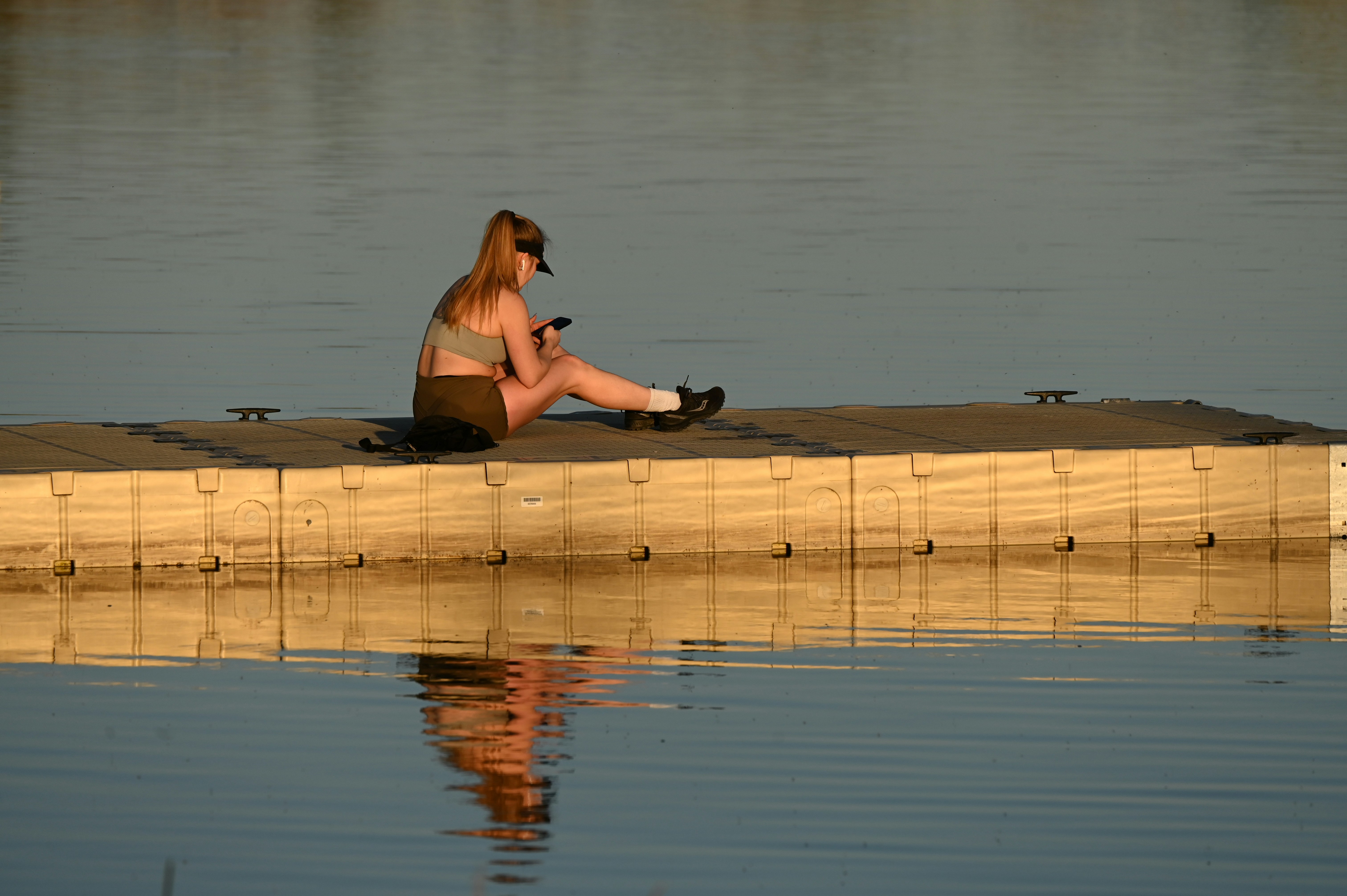 Une personne médite paisiblement au bord d'un lac au lever du soleil, symbolisant la connexion entre le bien-être mental et la santé corporelle.