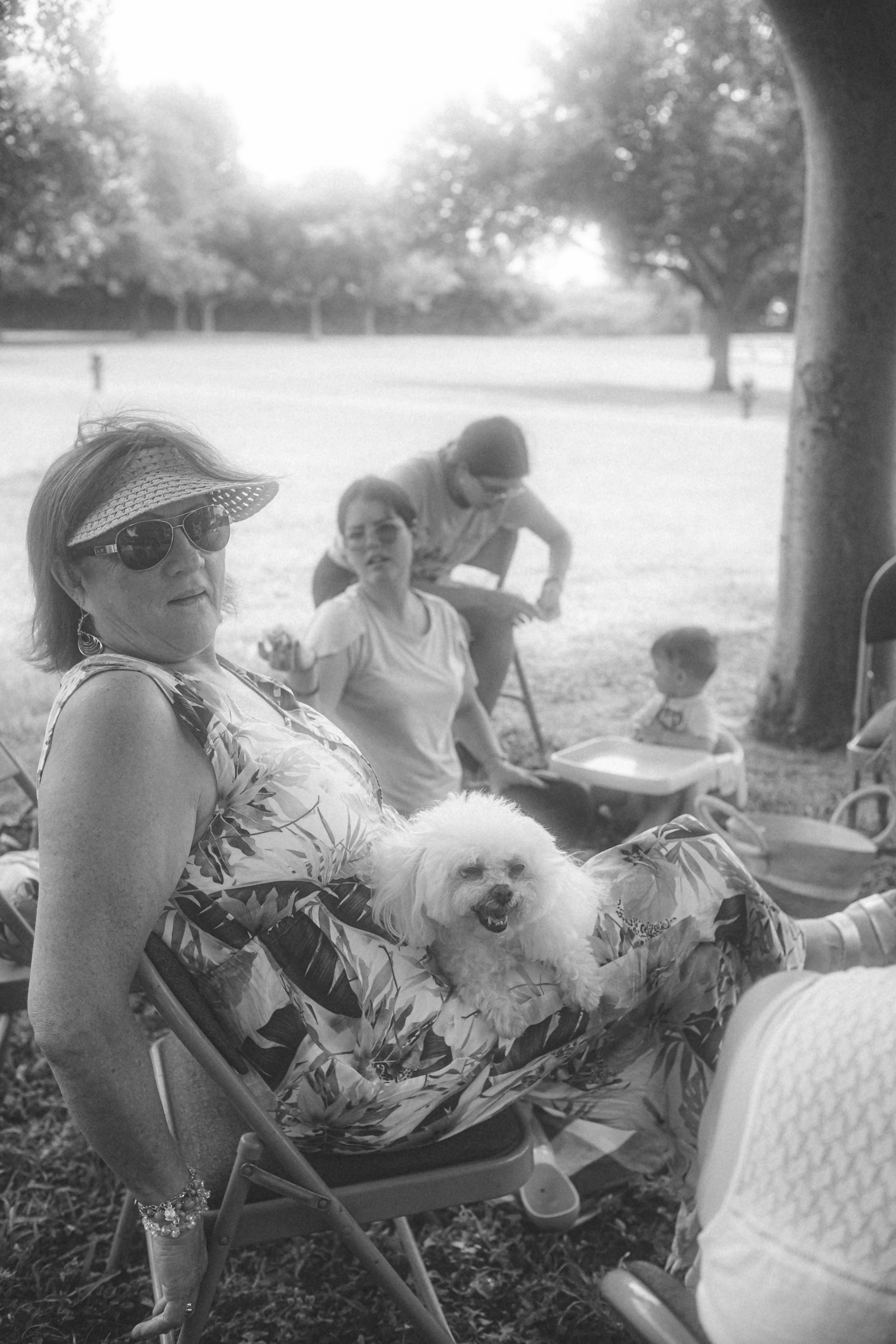 Une famille qui s'amuse et rit dans un parc ensoleillé, une photo pleine de vie et de joie spontanée.