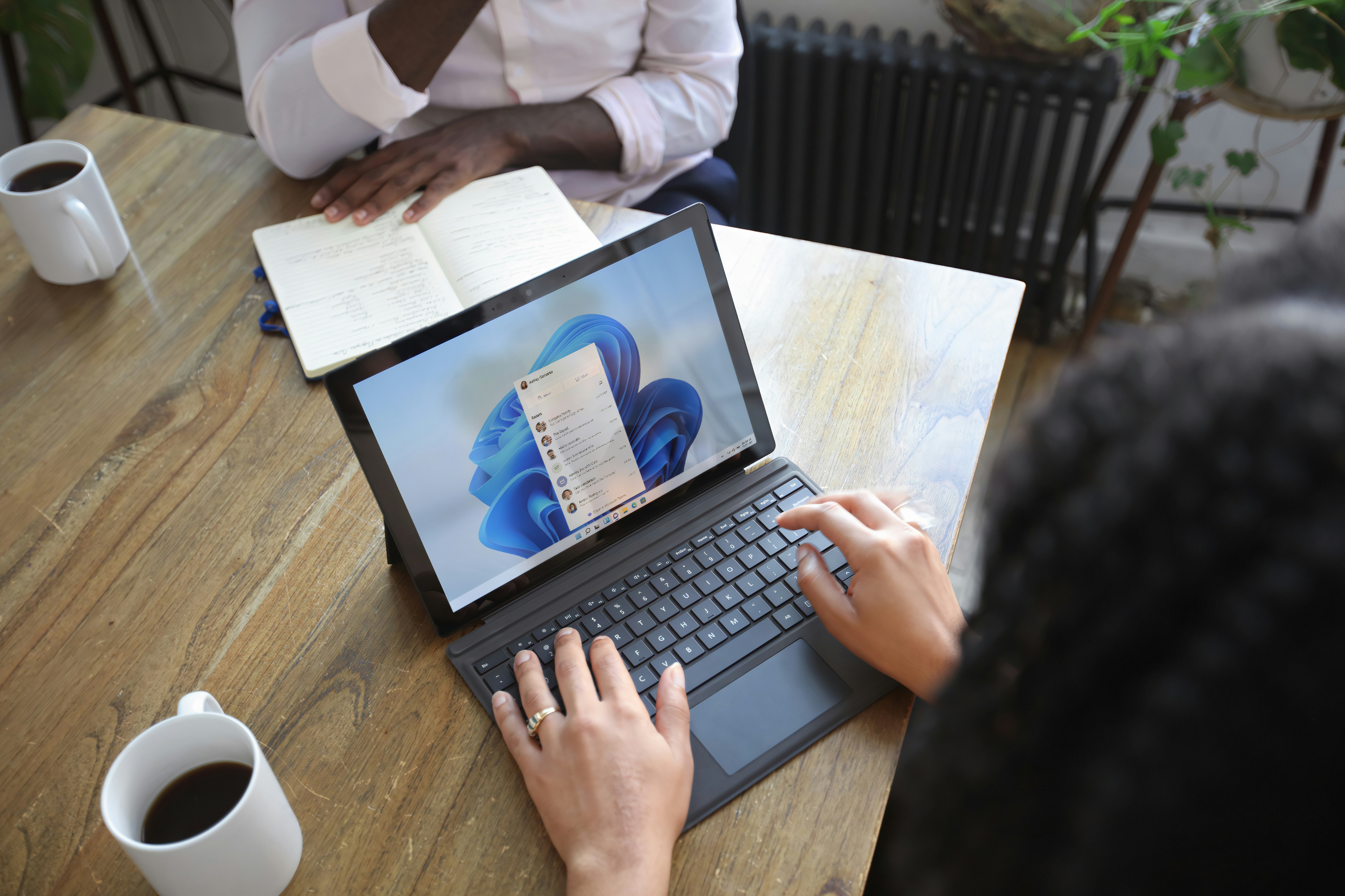 A diverse group of professionals collaborating in a meeting, with laptops and documents on the table.