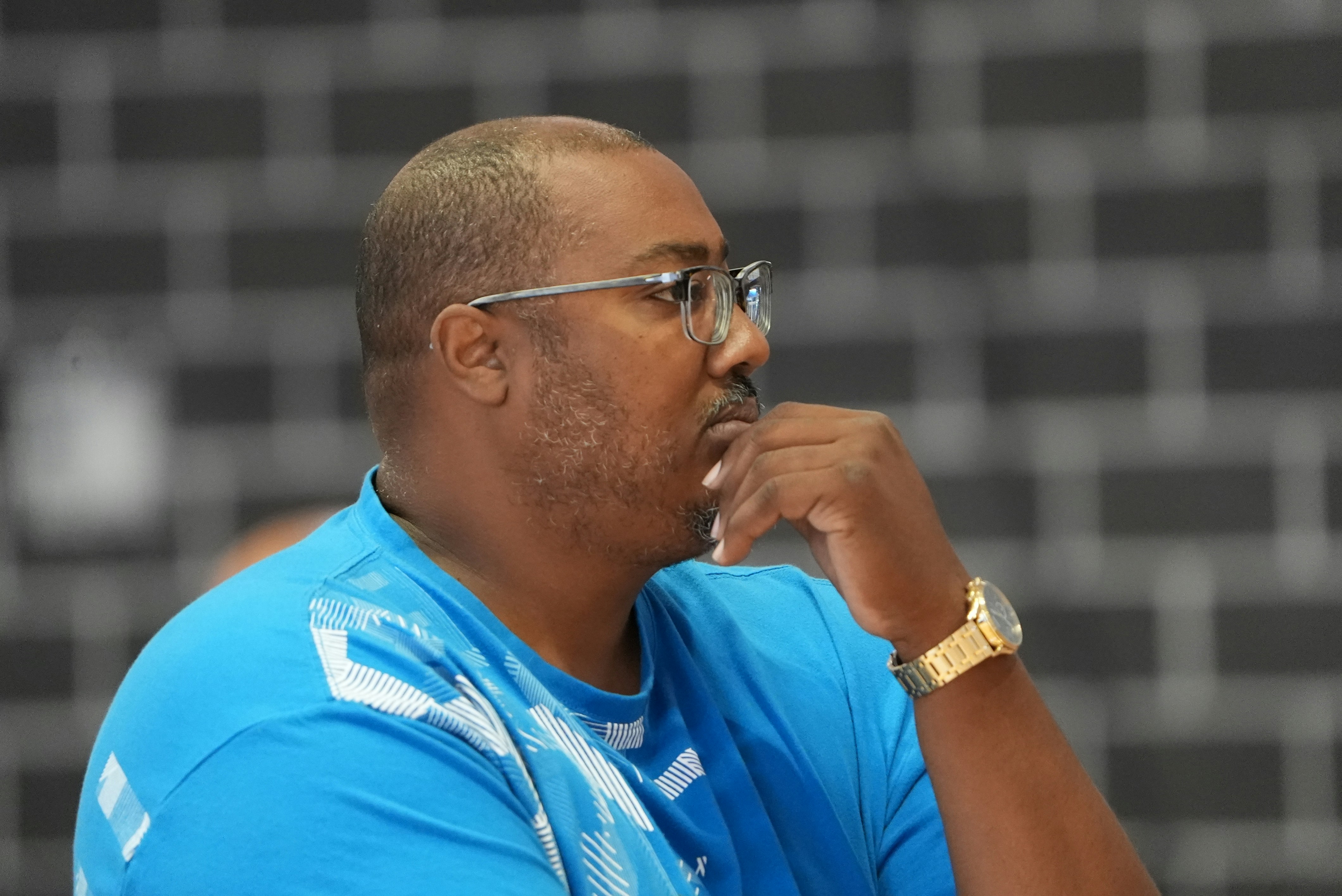 Un coach personnel souriant qui explique un mouvement à un client dans une salle de sport lumineuse et accueillante.