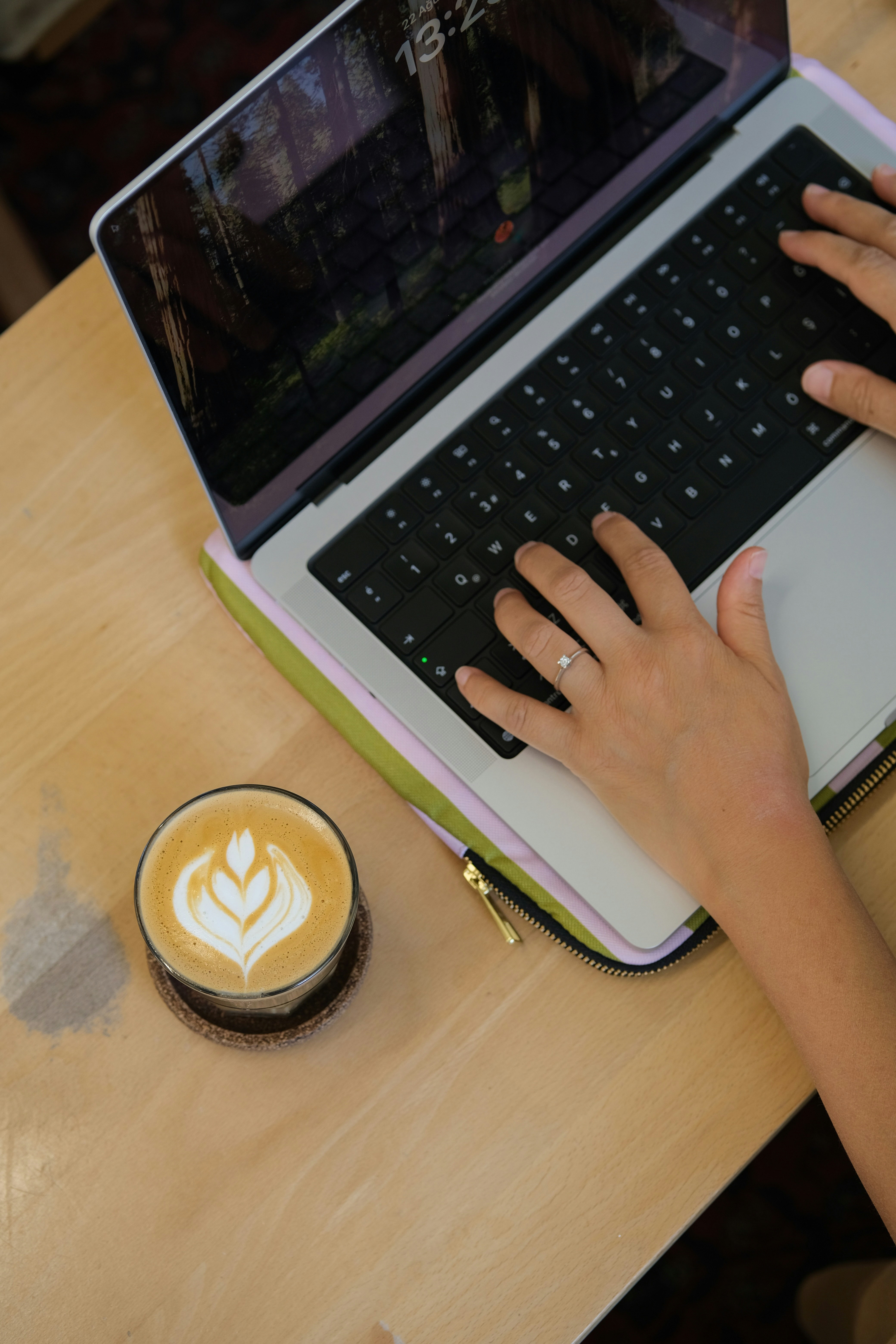A close-up of hands typing on a laptop at a cafe, with bits of code and design work on the screen.