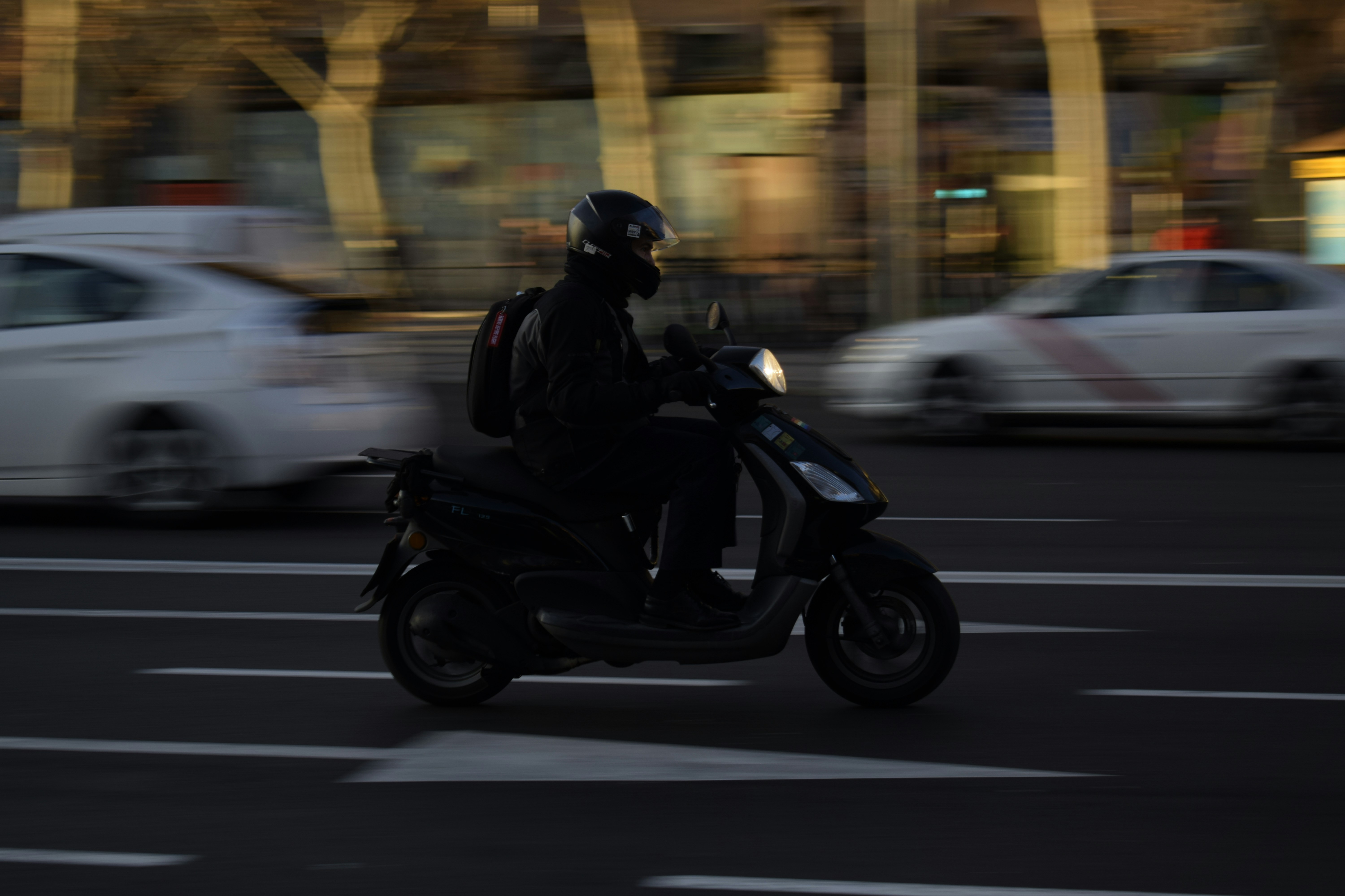 Une rue animée de Barcelone avec des voitures, des scooters et des piétons, illustrant une circulation dense.