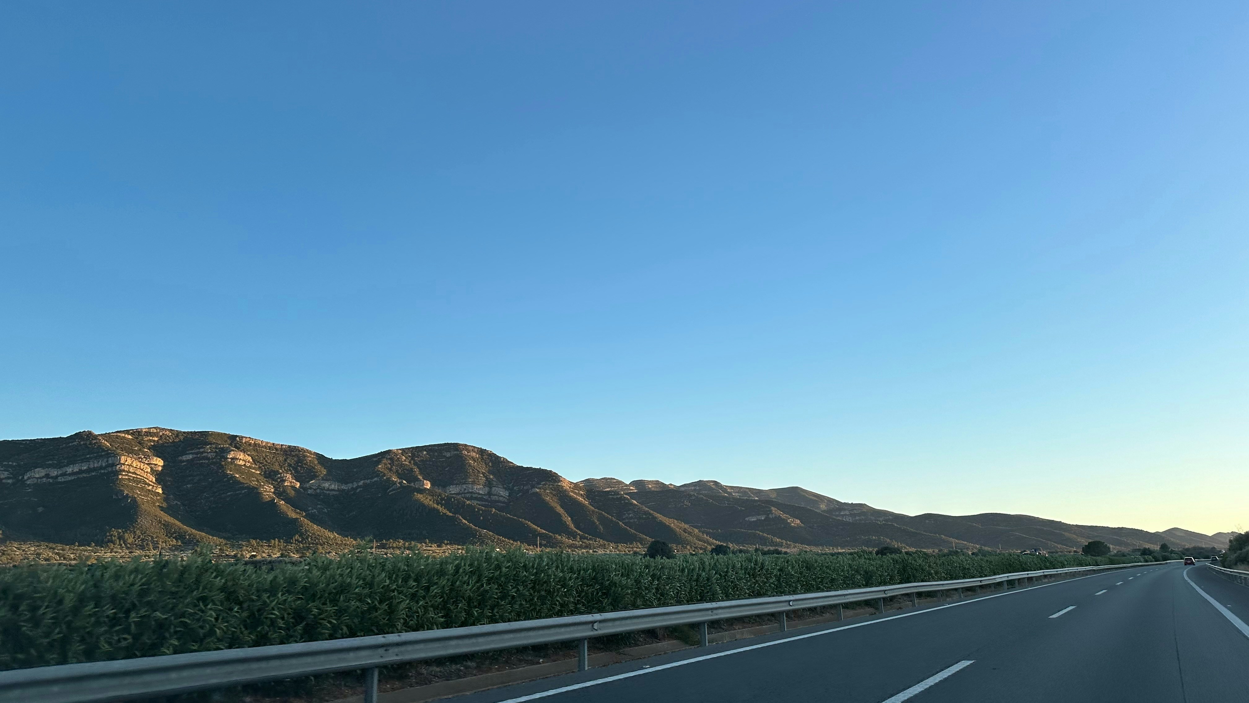 Une aire de repos sur une autoroute française ou espagnole, avec des voitures garées et des gens se reposant.