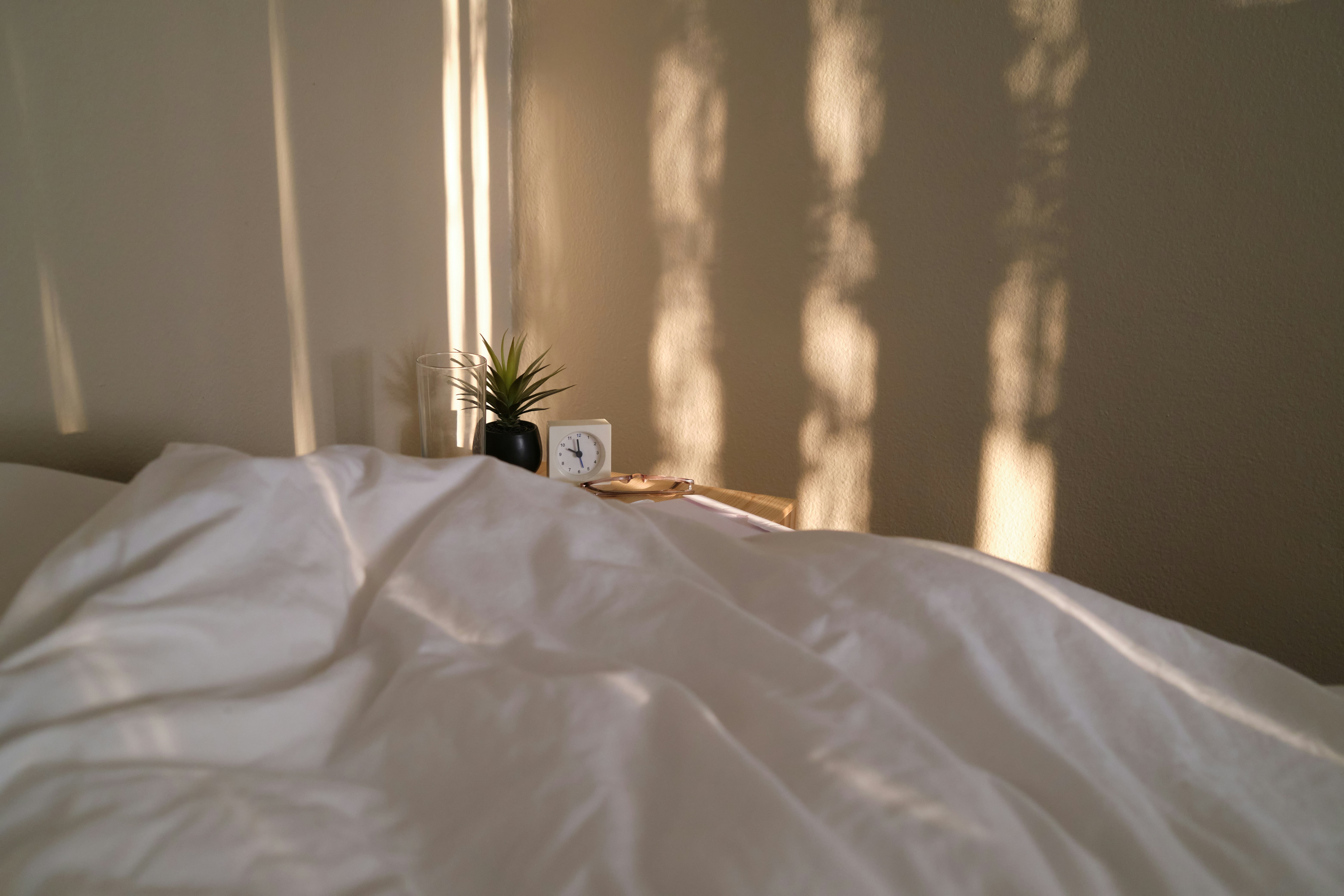 Une chambre à coucher minimaliste avec une grande fenêtre habillée d'un store jour nuit en position presque fermée, créant une atmosphère reposante et privée.