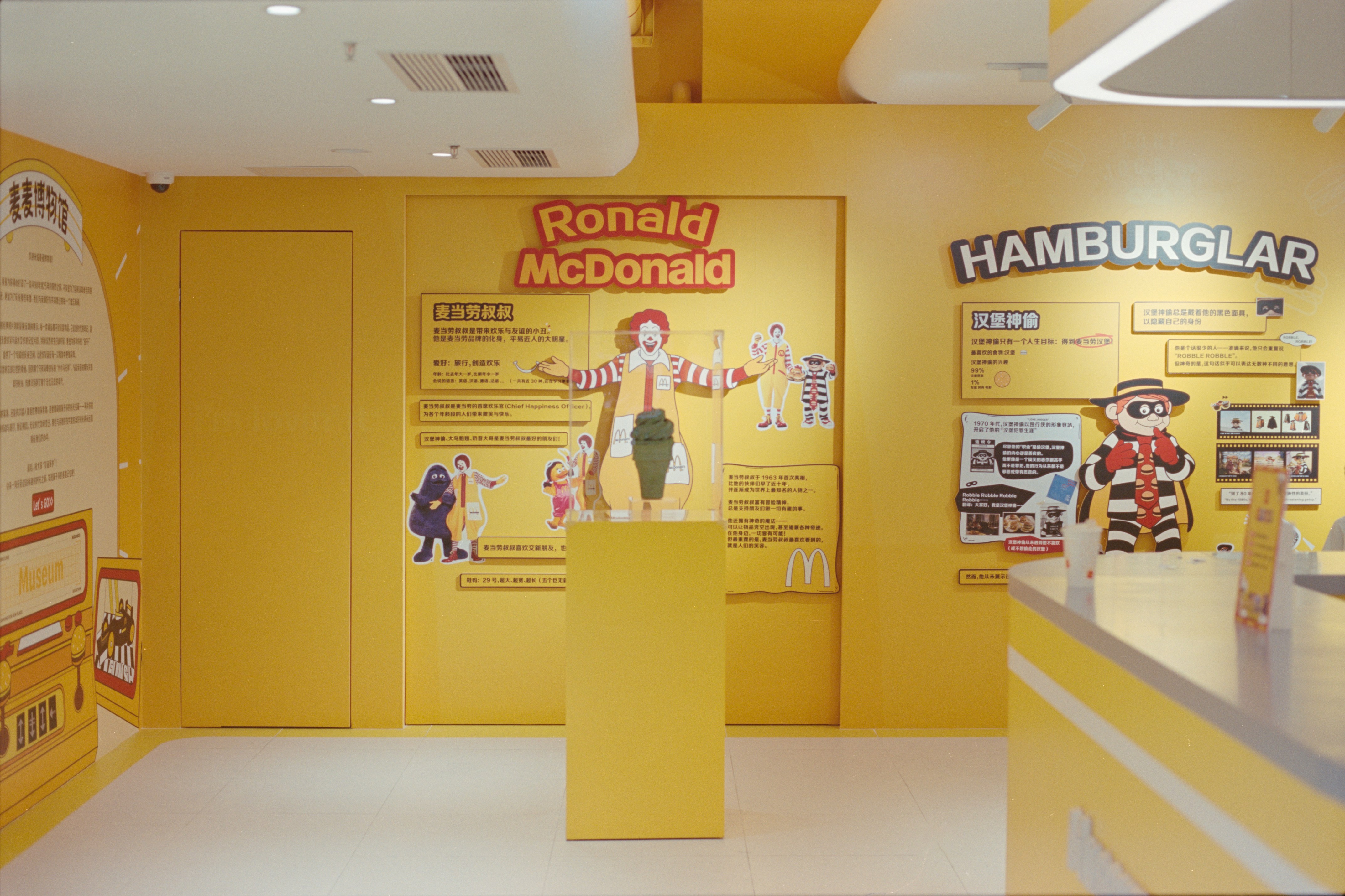 Une animation commerciale dans un centre commercial bondé. Des enfants participent à un atelier créatif tandis que les parents regardent, souriants. L'ambiance est joyeuse et animée.