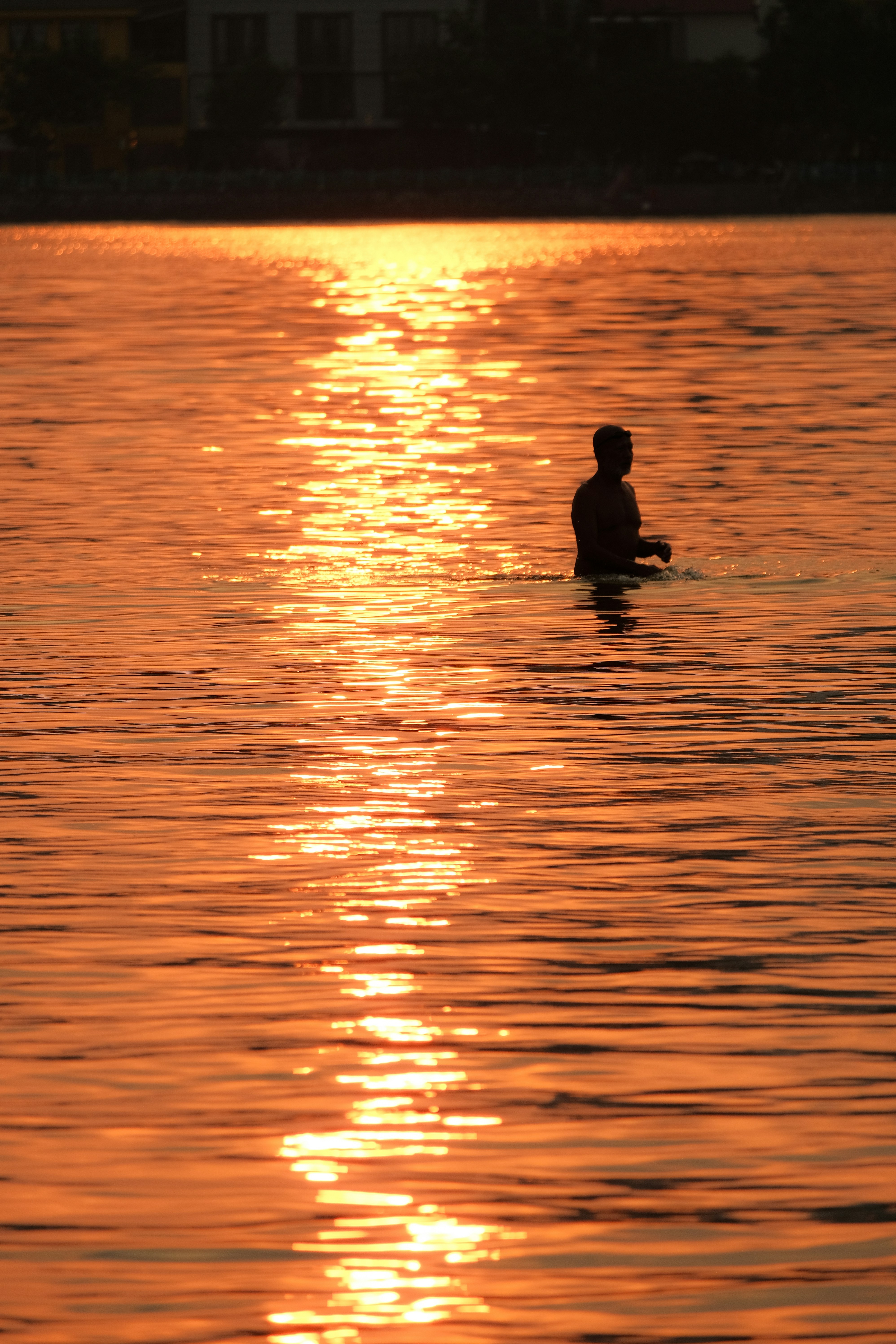 Une personne qui médite, tranquille, face à une grande baie vitrée avec une vue sublime sur le lac Léman au coucher du soleil.
