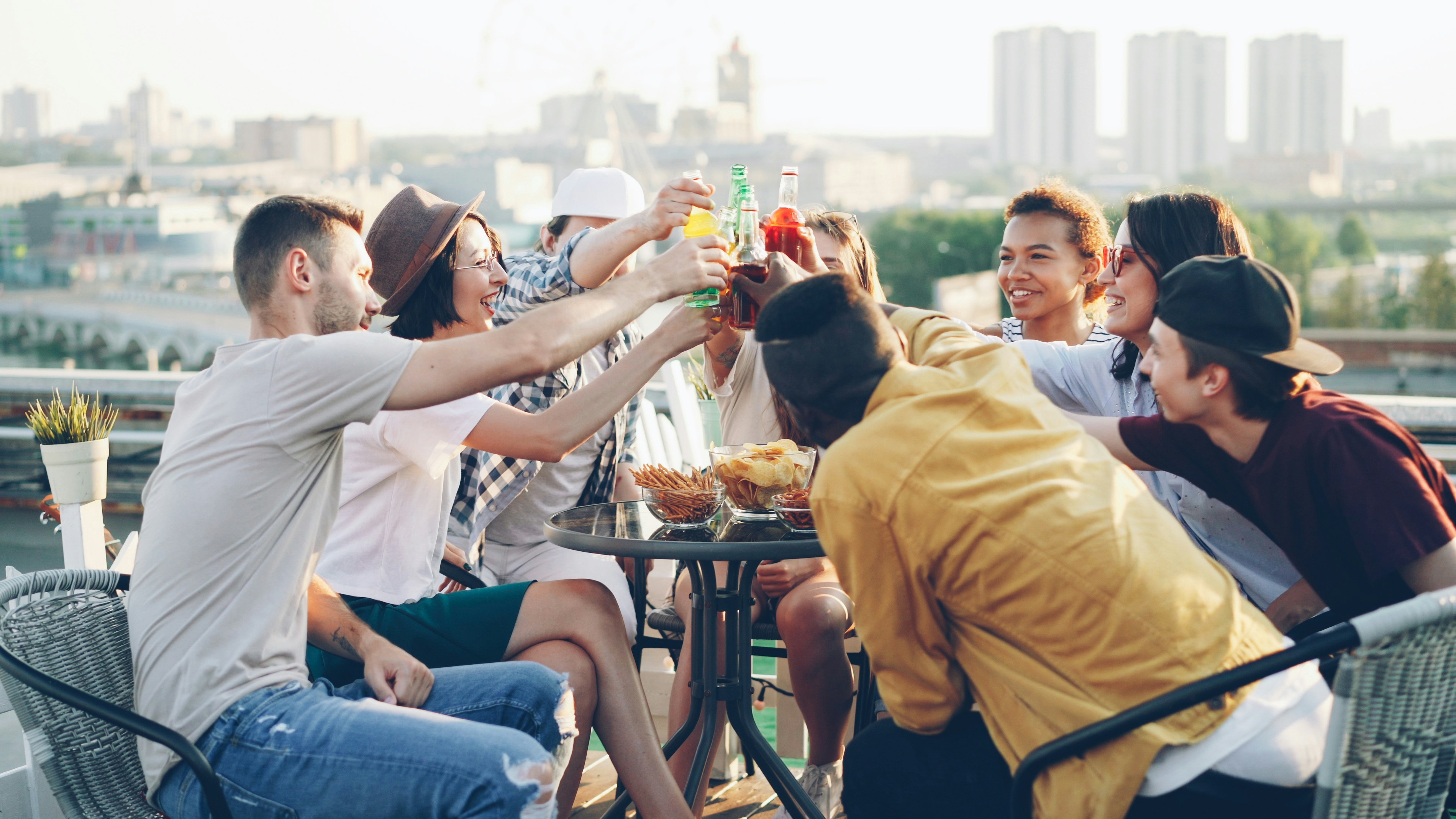 Un groupe de personnes diverses riant et partageant des boissons dans un parc, mettant en évidence les aspects sociaux et communautaires de la marque.