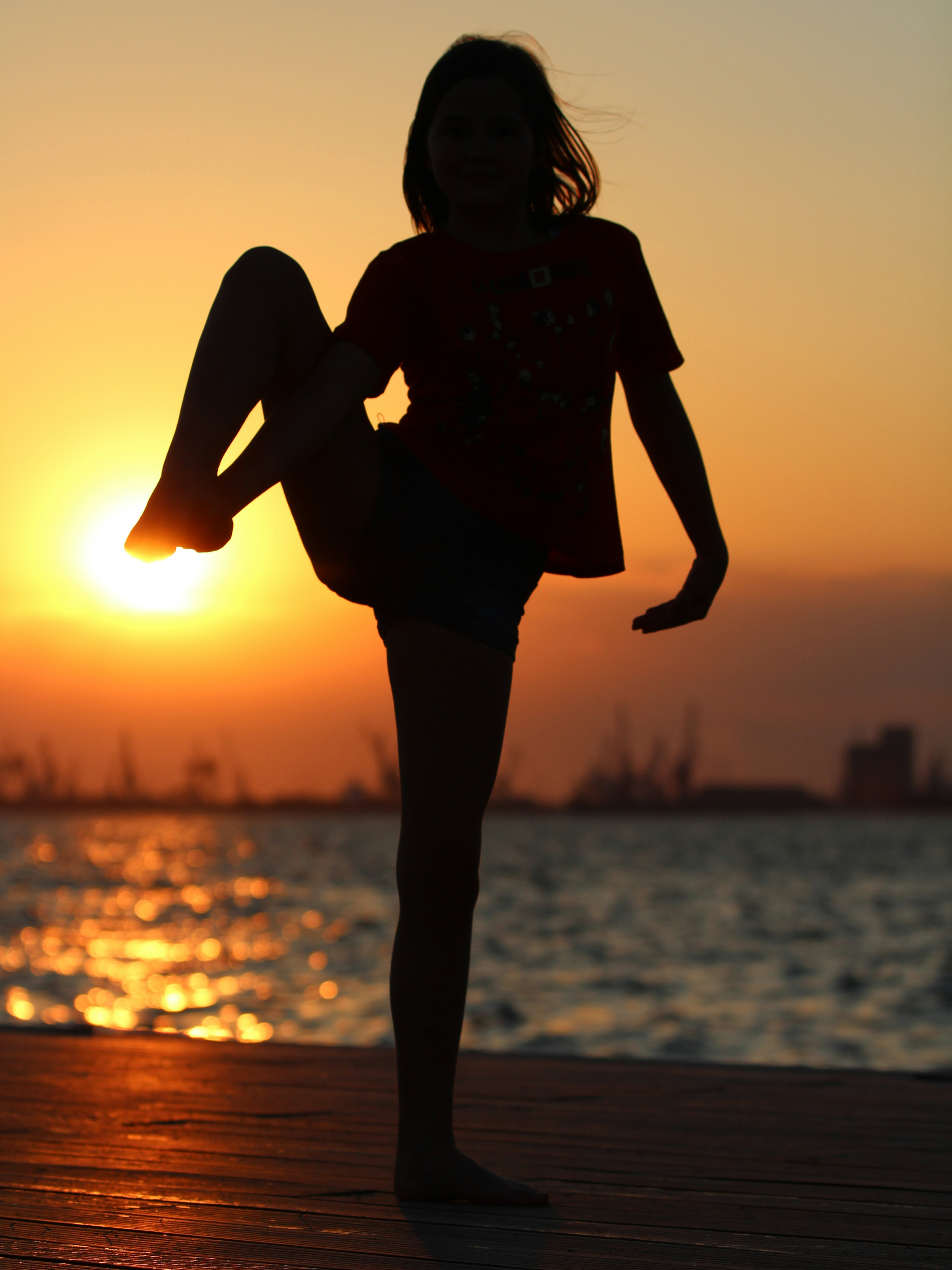 A female dancer in a graceful pose in an urban park setting, with soft morning light.