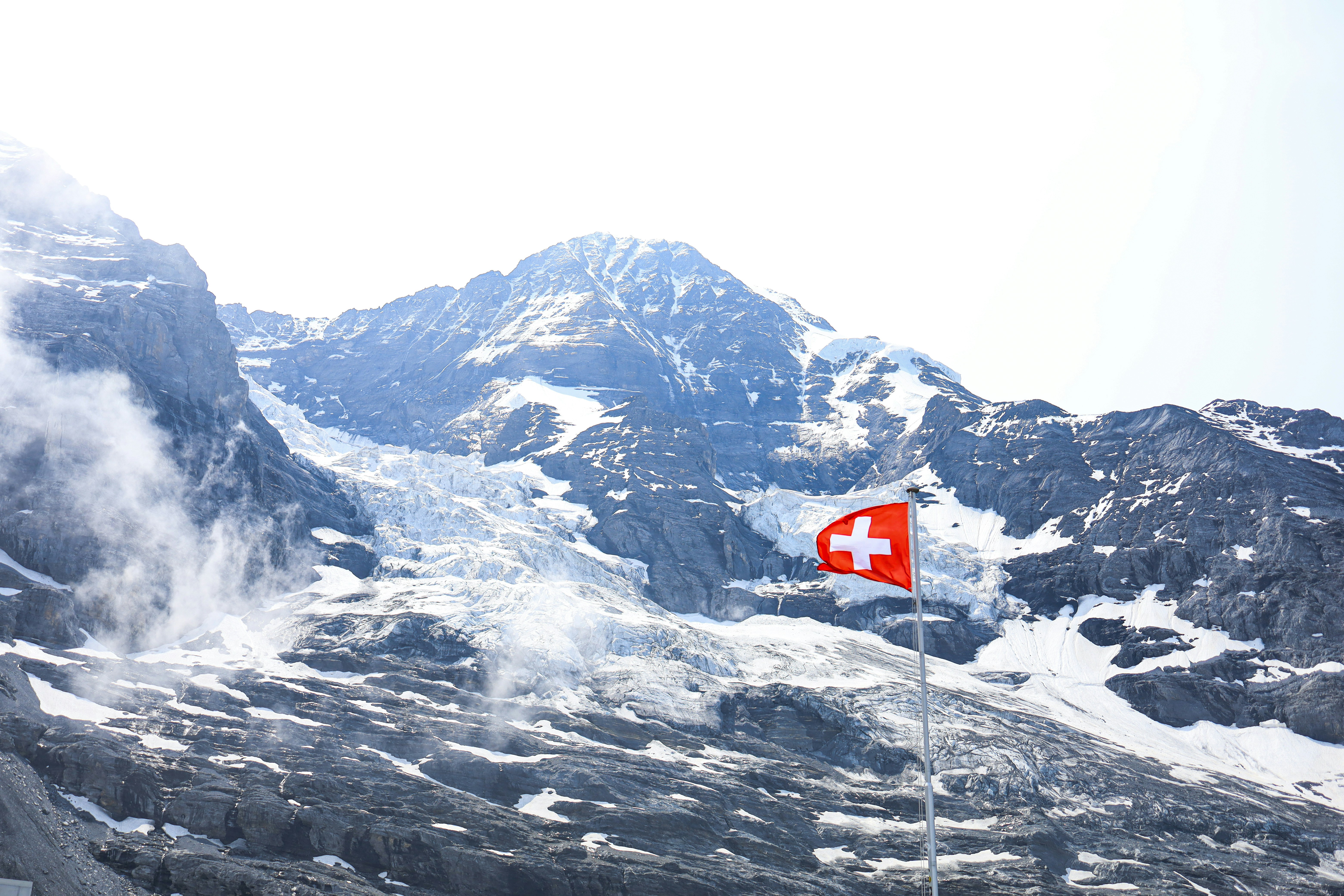 Le drapeau suisse qui claque au vent, avec les Alpes derrière. L'image parfaite de la confiance, de la qualité et des spécificités du marché suisse.