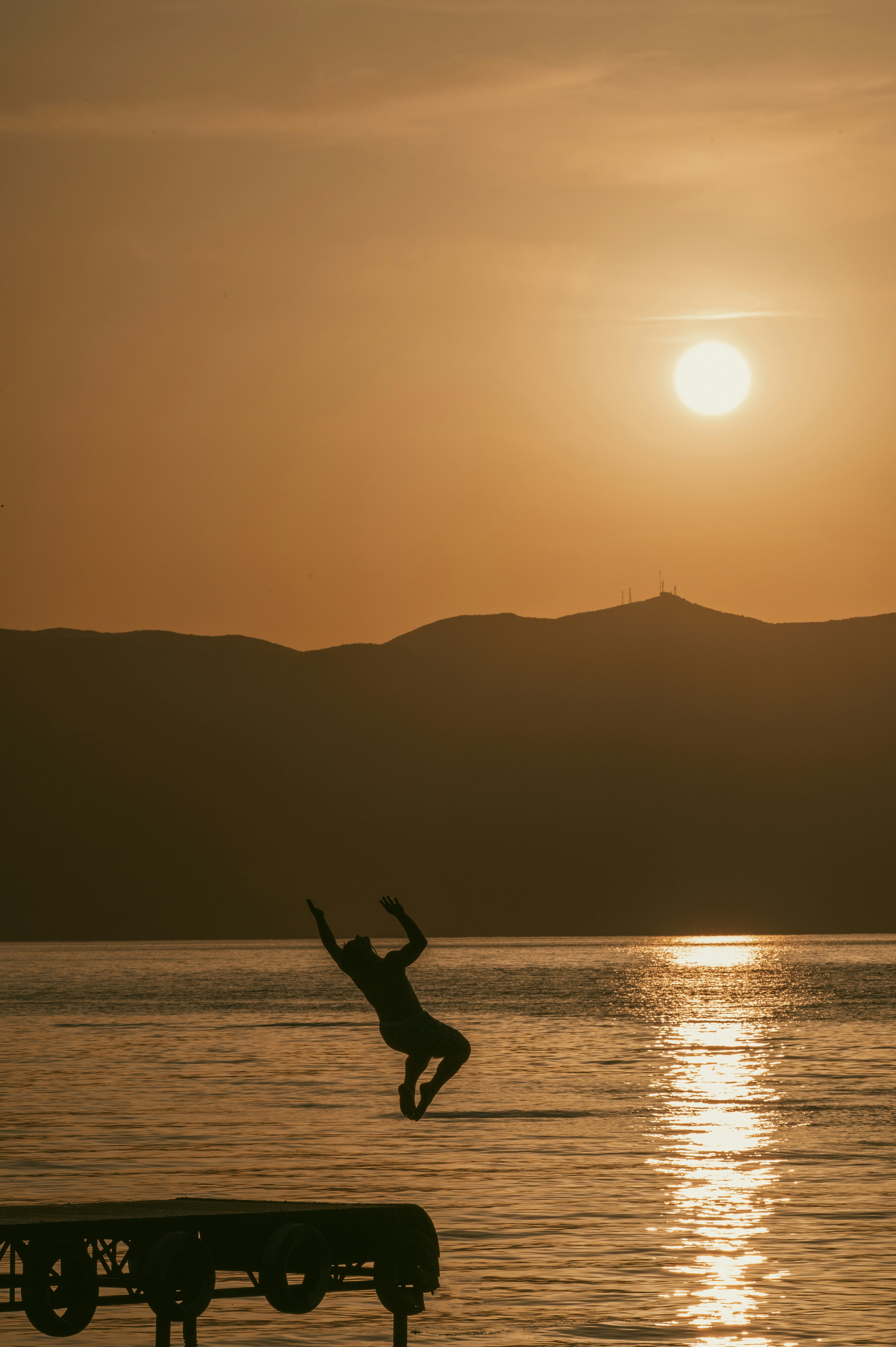 Une personne méditant en posture de yoga face à un lac de montagne suisse au lever du soleil, évoquant la paix et l'harmonie avec la nature.