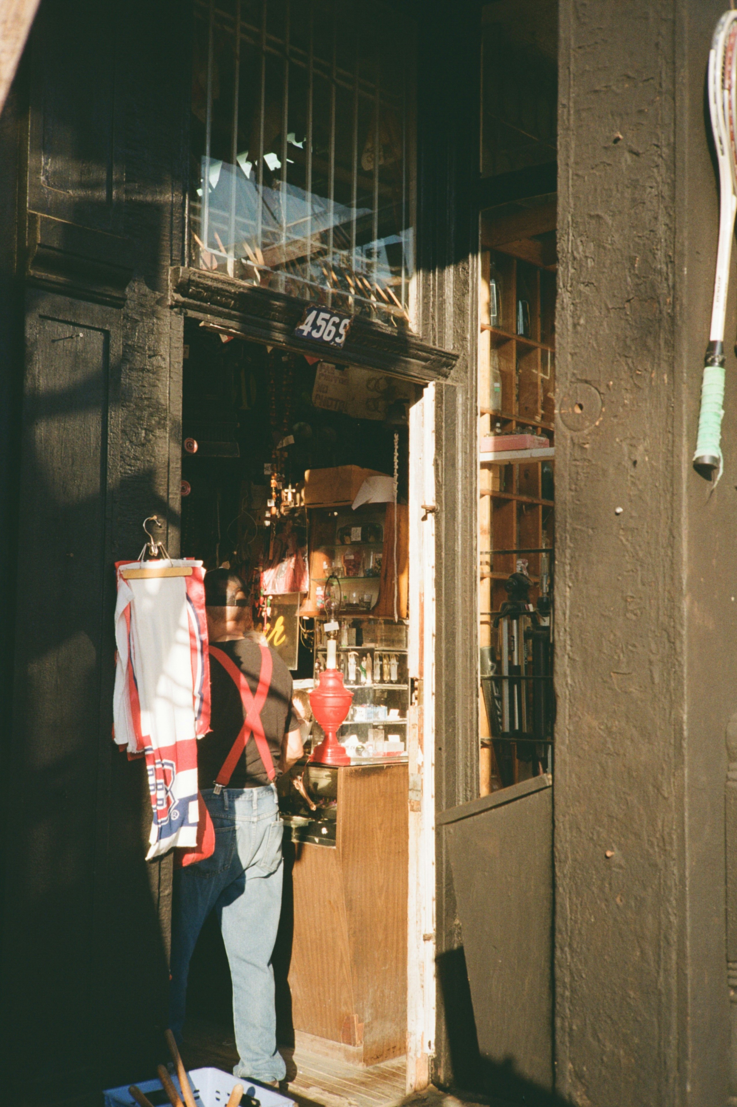 Une propriétaire de petite boutique souriante, se tenant fièrement devant son magasin bien achalandé, évoquant la satisfaction et le succès du commerce local.