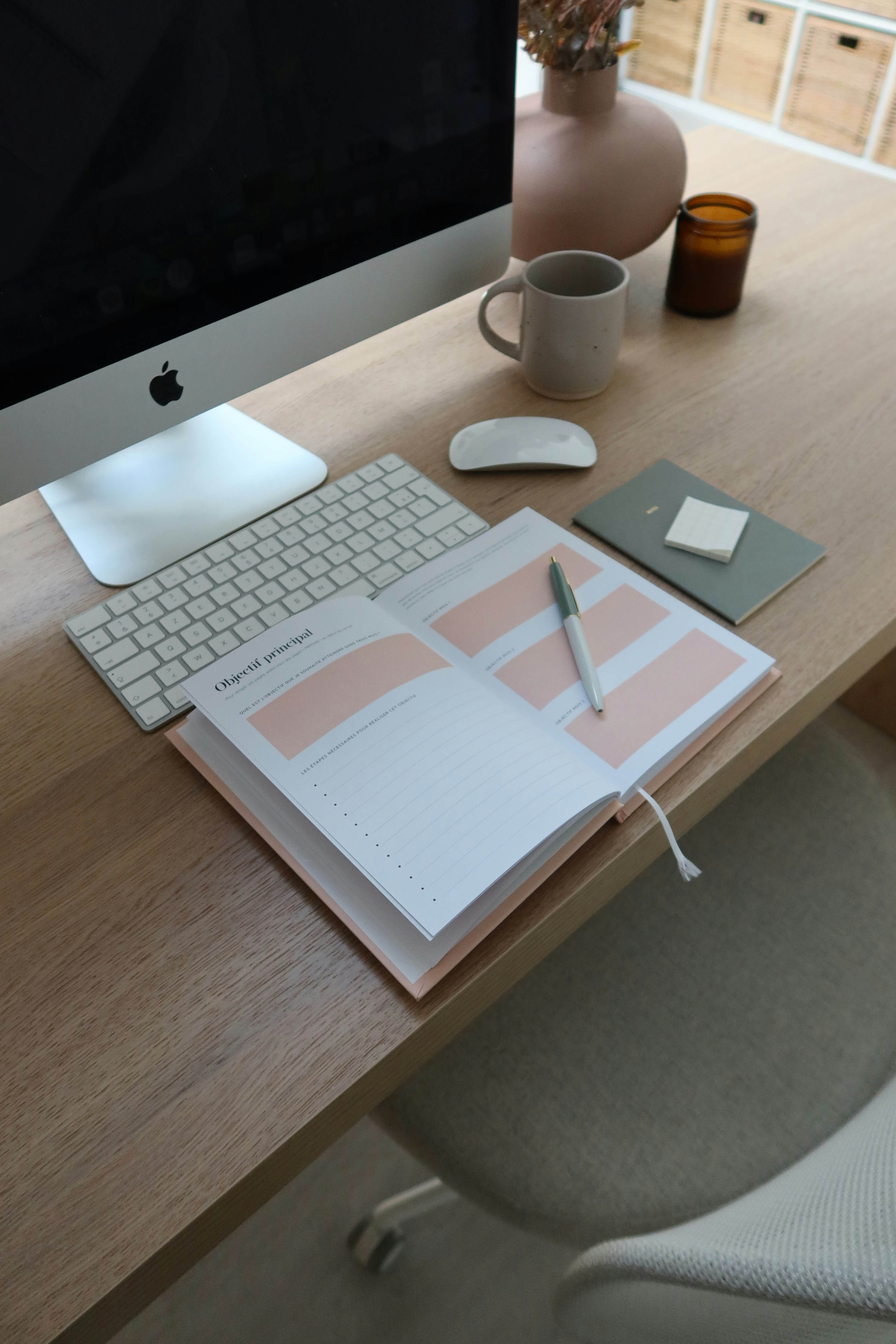 A simple, clean shot of a laptop on a wooden desk with a notebook and pen next to it, giving a sense of writing and planning.