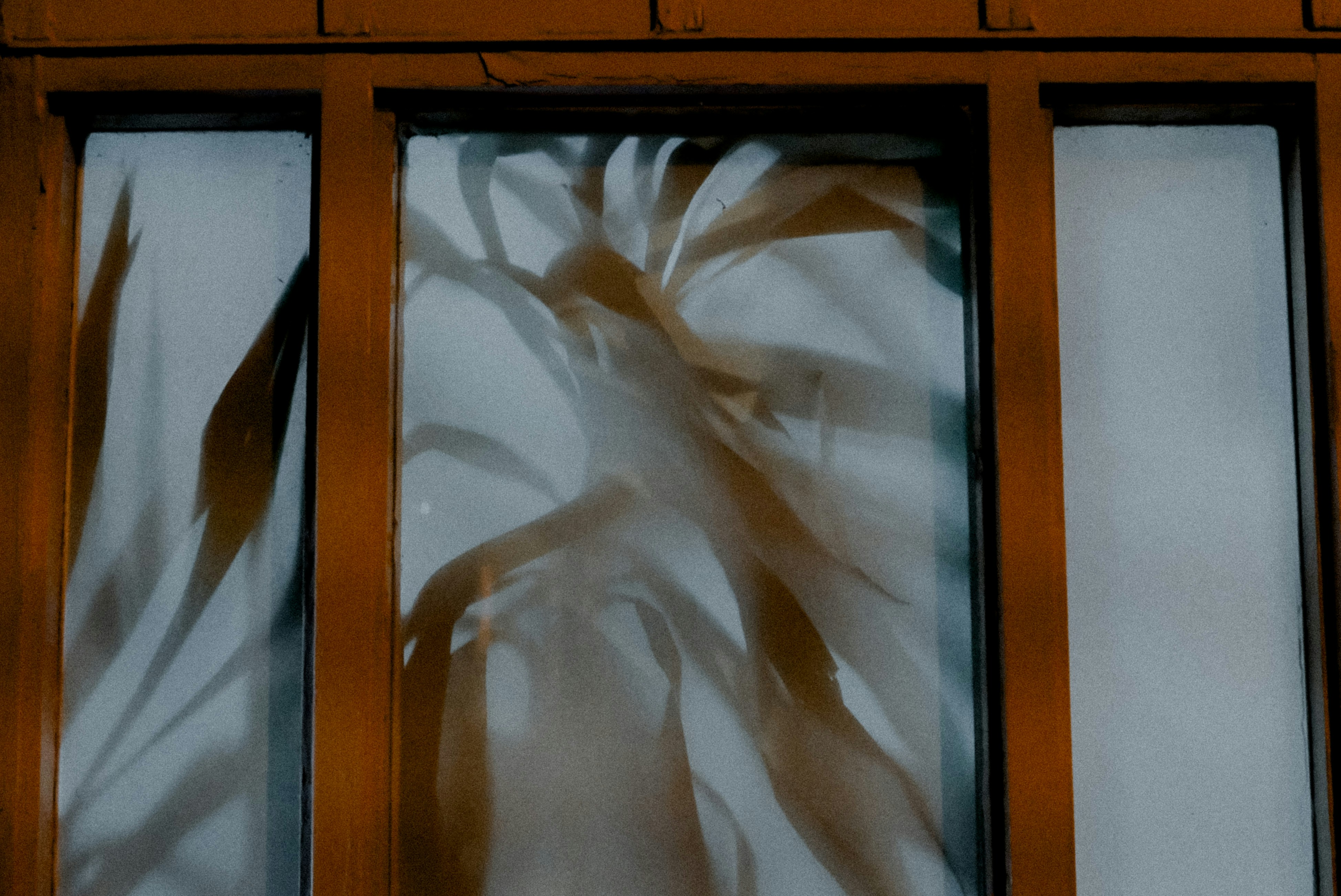 Un peintre professionnel appliquant du ruban de masquage avec précision autour d'un cadre de fenêtre dans un bureau.