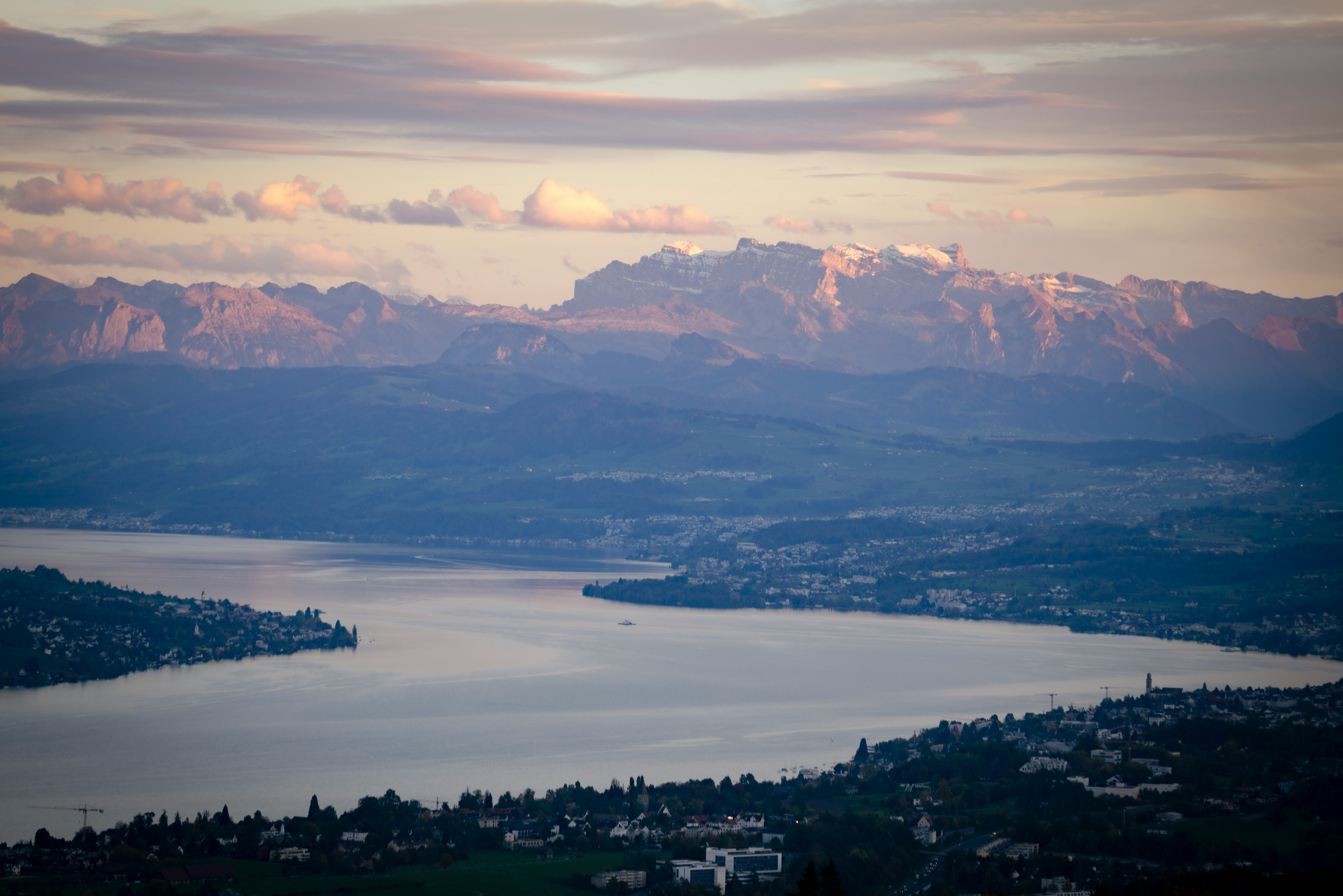 Vue panoramique du lac Léman avec les Alpes en arrière-plan, symbolisant l'ancrage local en Suisse romande.