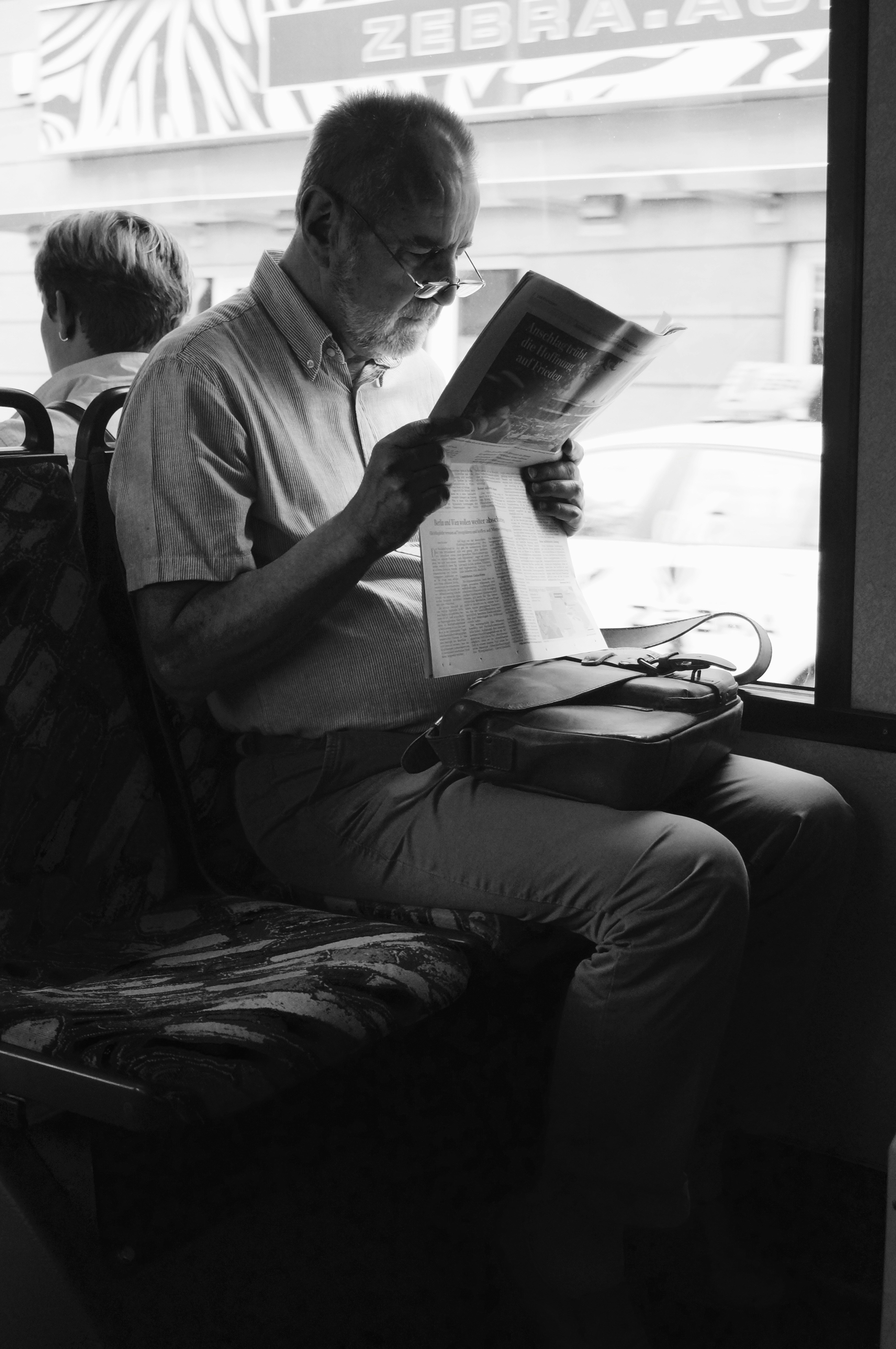 Un homme d'affaires élégant dans un train regardant par la fenêtre, un petit livre de poche posé sur la table à côté de lui.