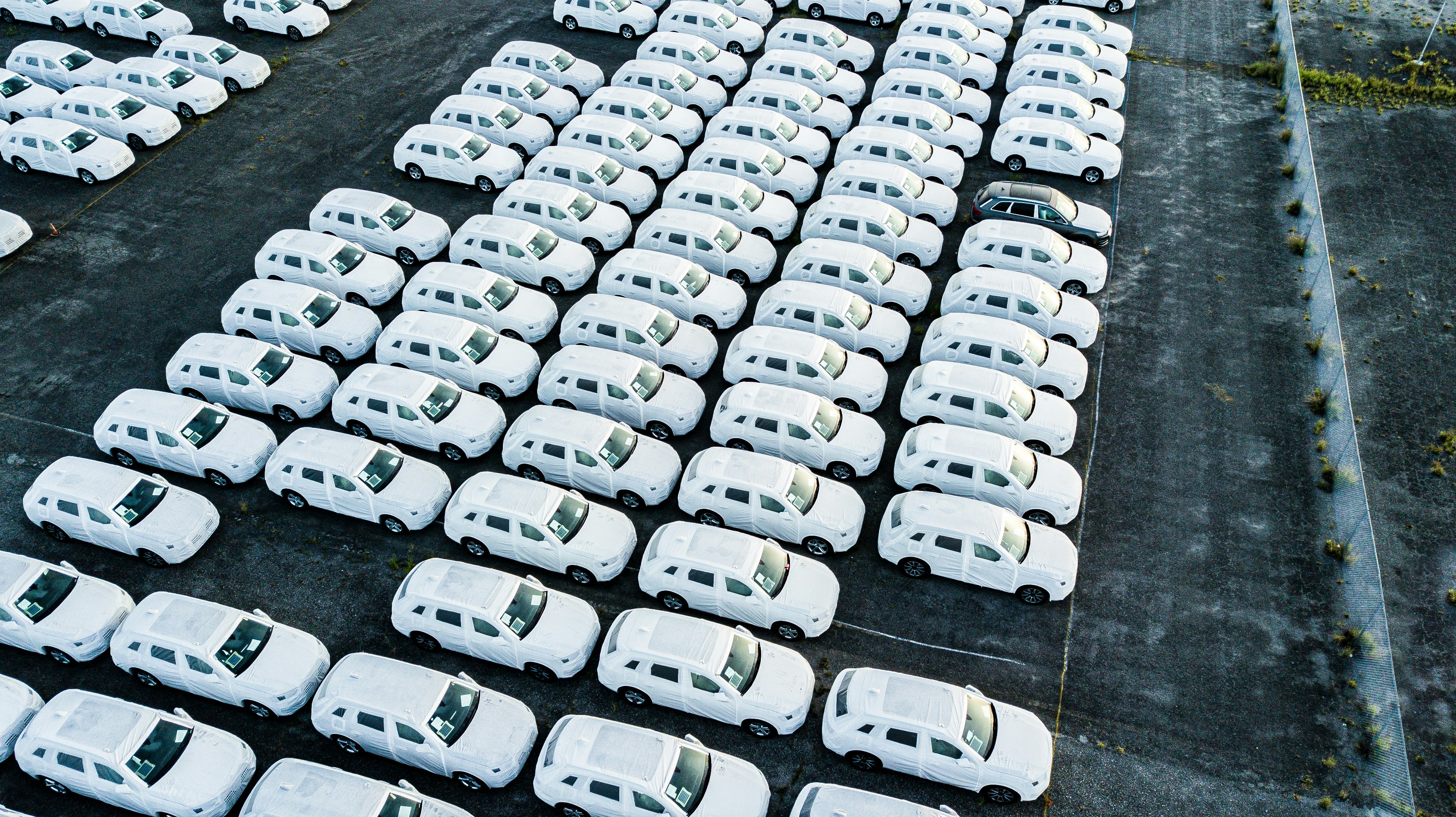 Une flotte de fourgonnettes de livraison blanches, propres et uniformes, garées en rangées nettes.