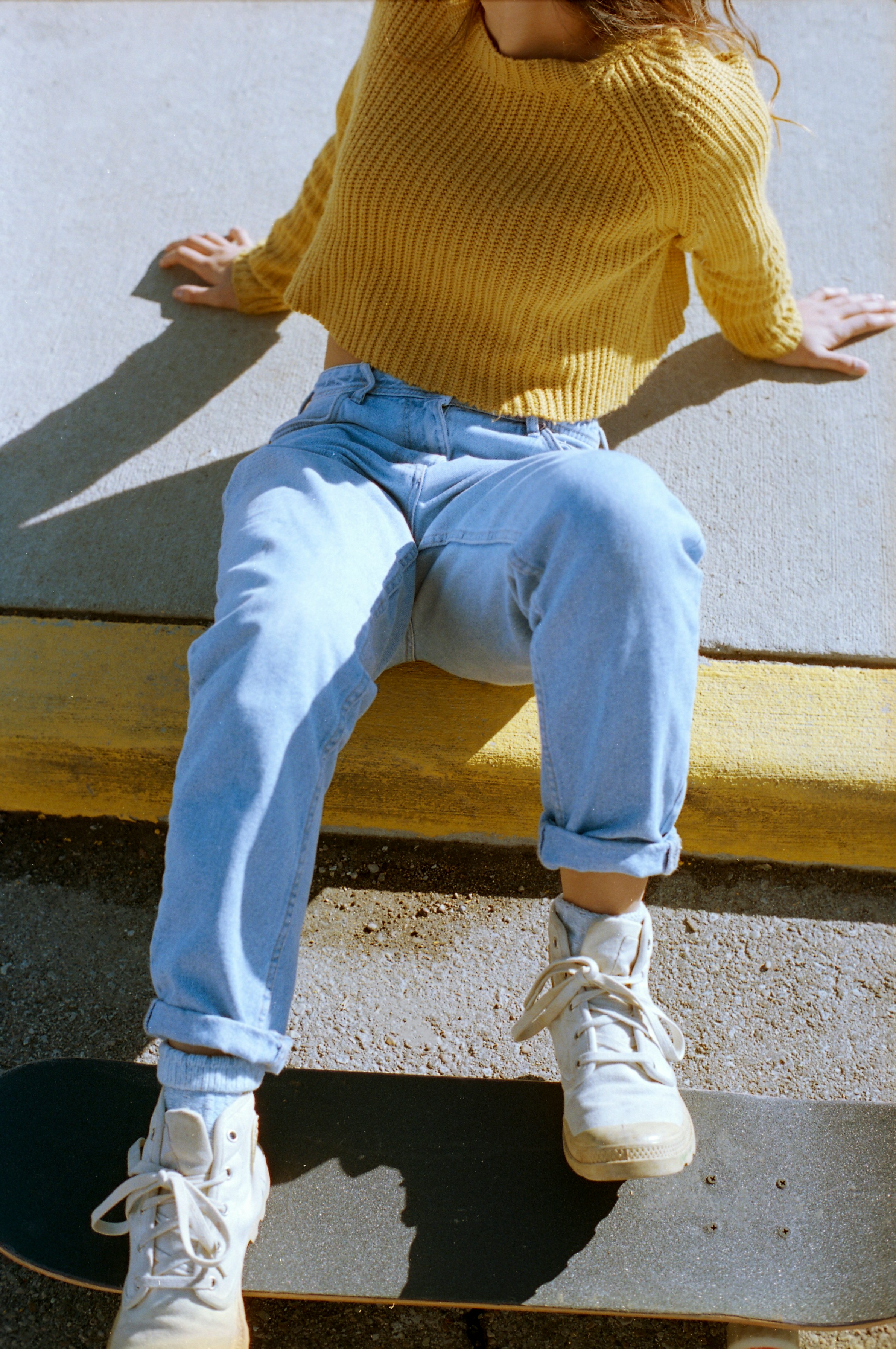 Une femme ajustant les couches de sa tenue, un pull léger sur une chemise, avec un jean.