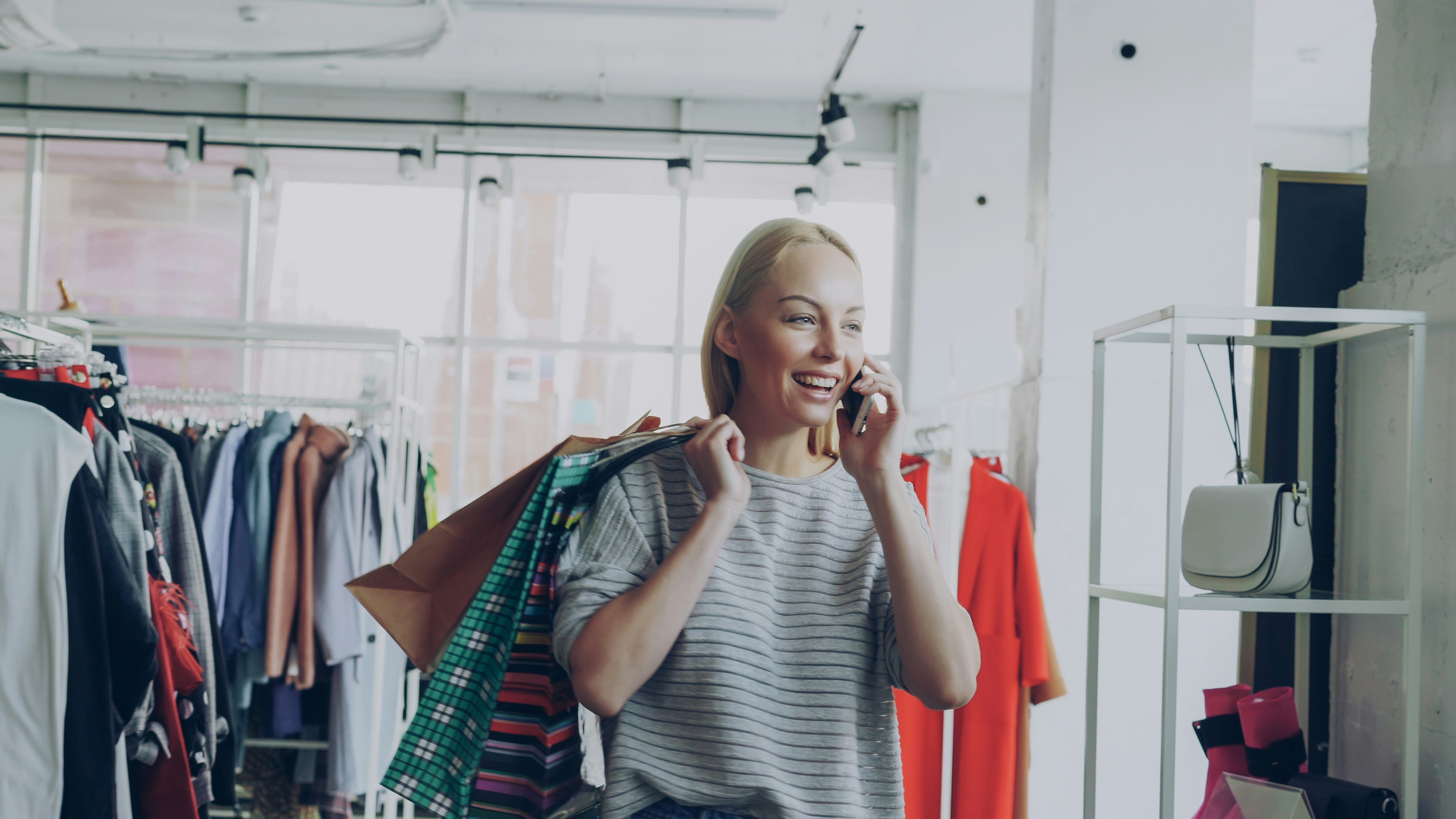Une femme choisissant des vêtements sur un portant dans une boutique lumineuse et aérée.