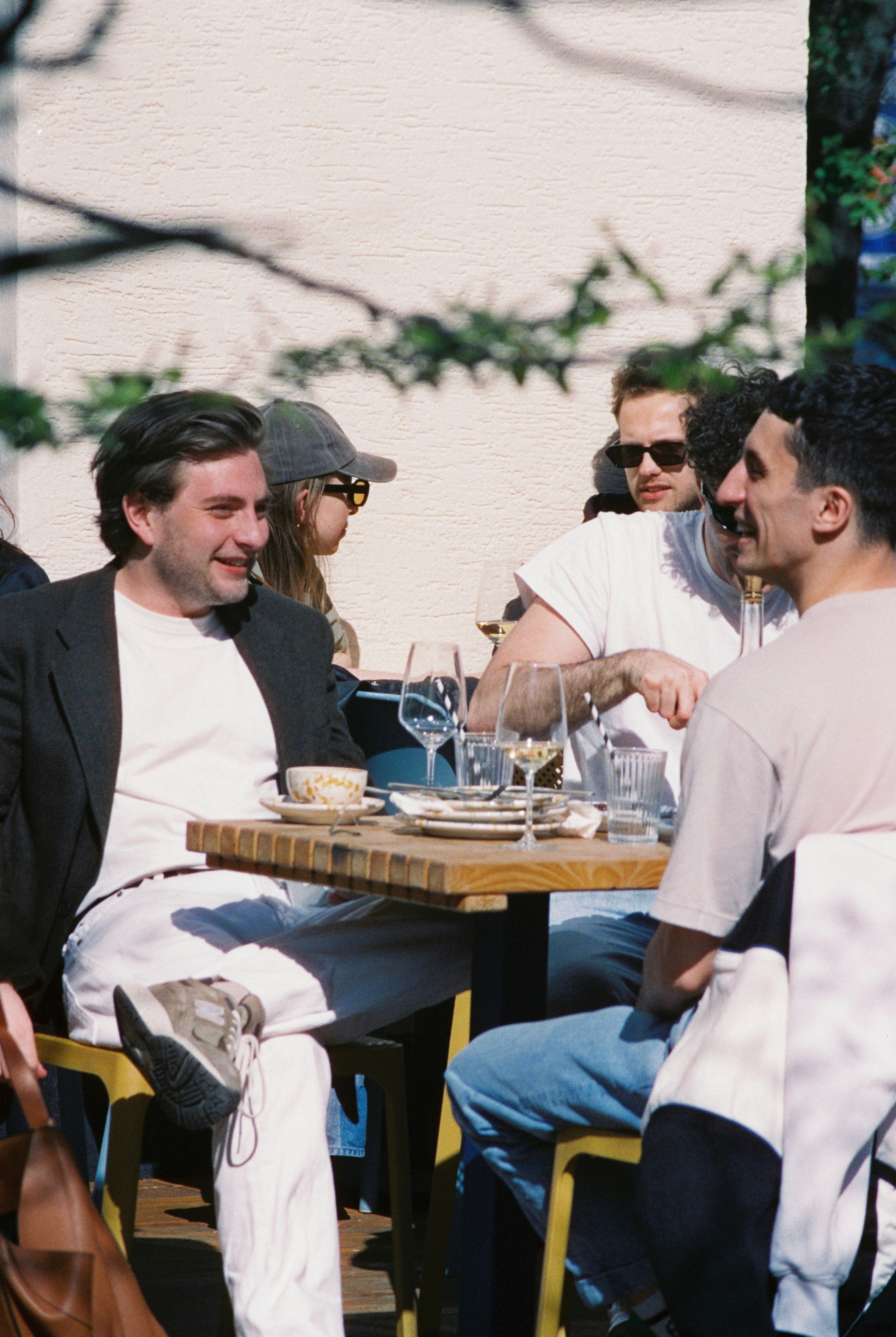 Groupe d'amis diversifié riant et discutant autour d'une table dans un bar animé.