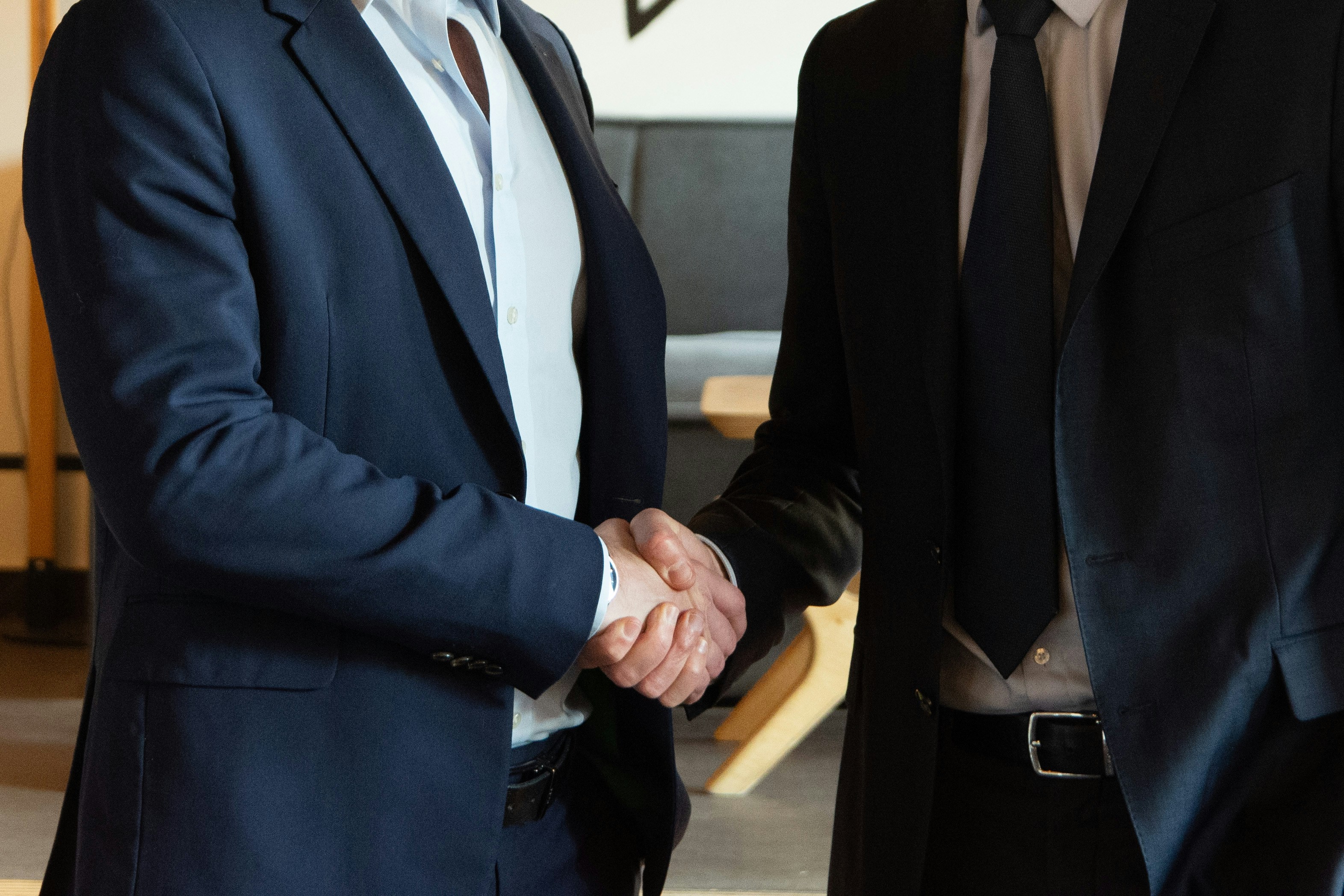 Two smiling digital marketing pros shaking hands in a bright office, sealing a deal on a new partnership or successful client win.