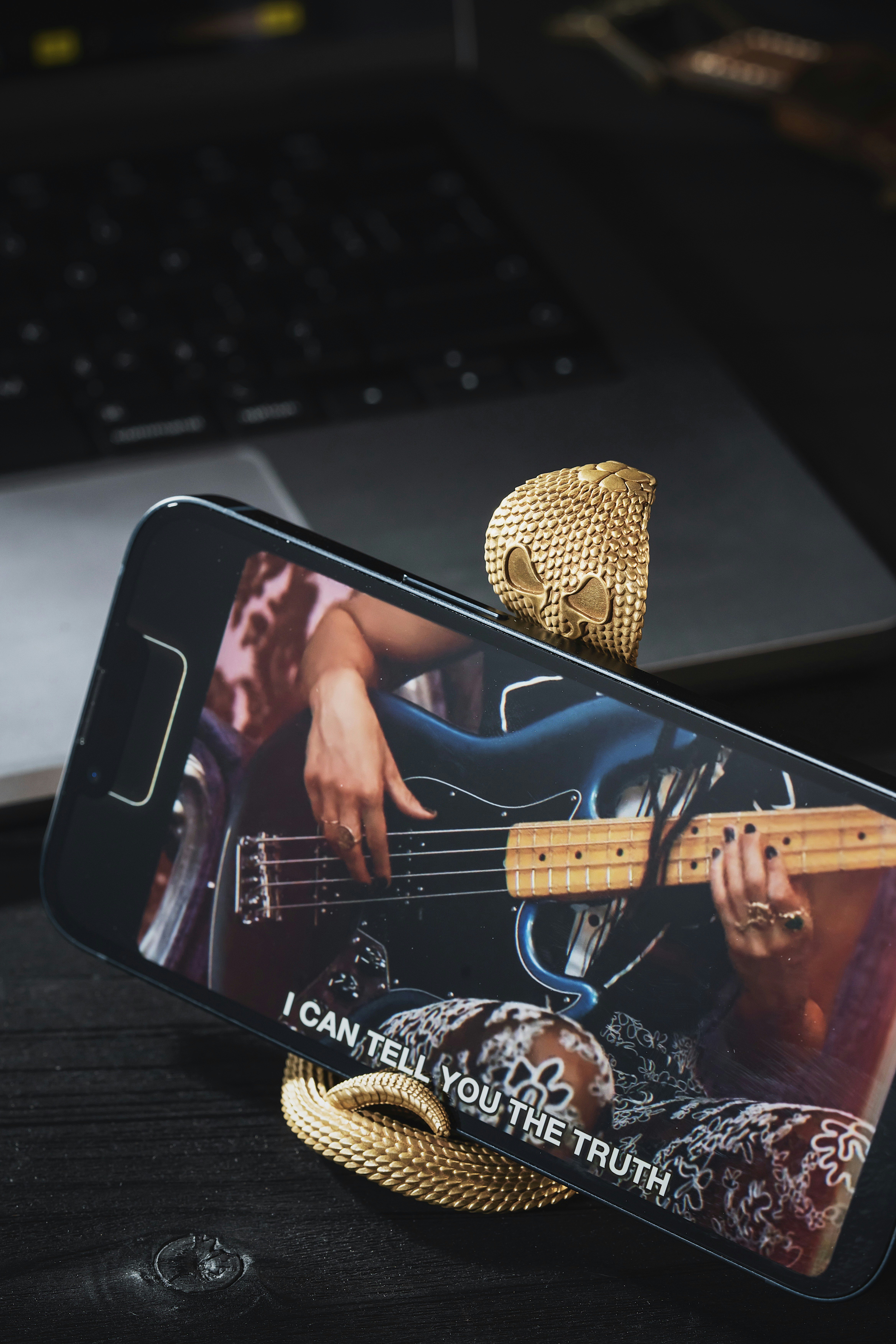 Close up of a hand tuning a guitar headstock with a smartphone app visible in the background