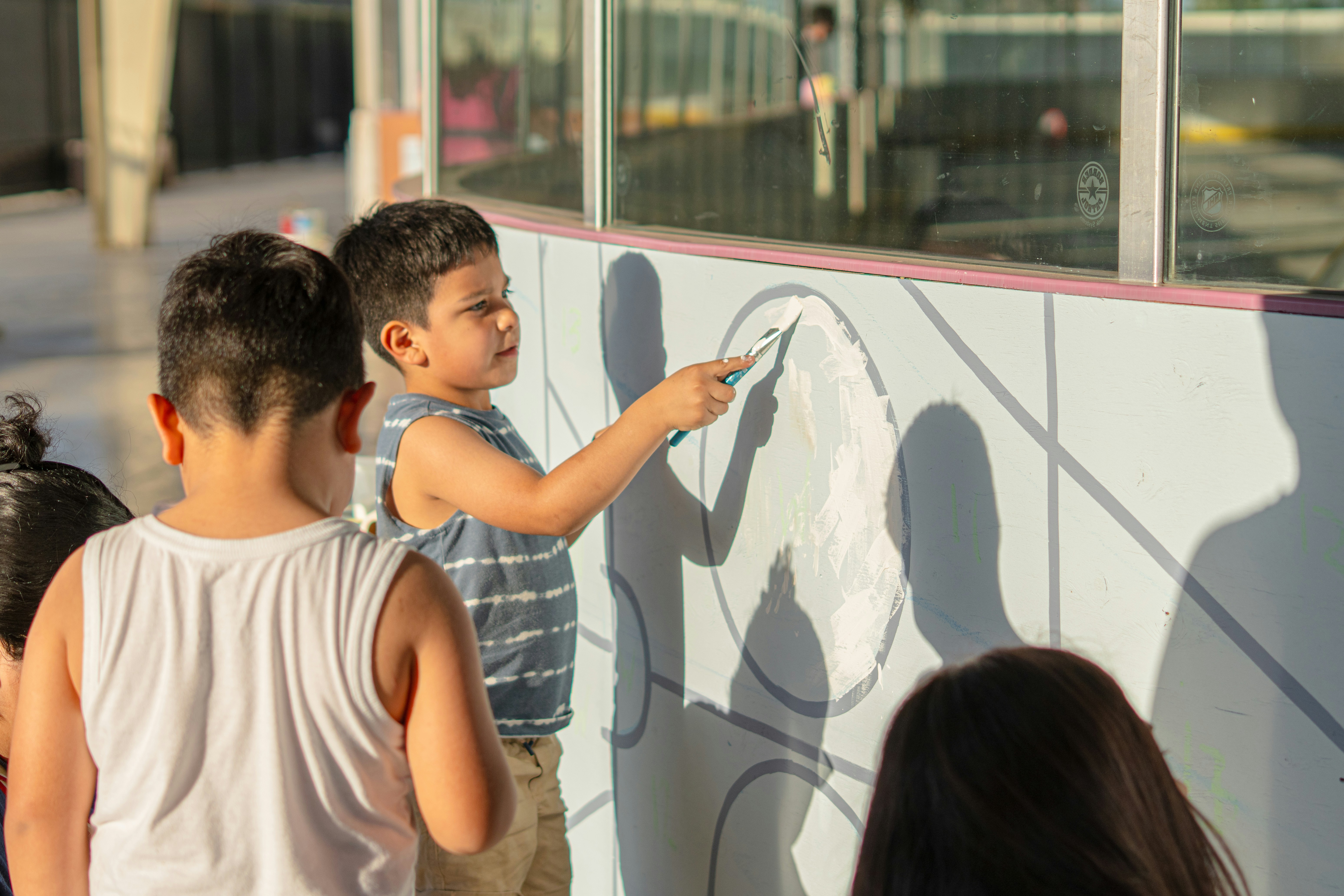 Children participating enthusiastically in a creative workshop inside a shopping mall with colorful decorations.