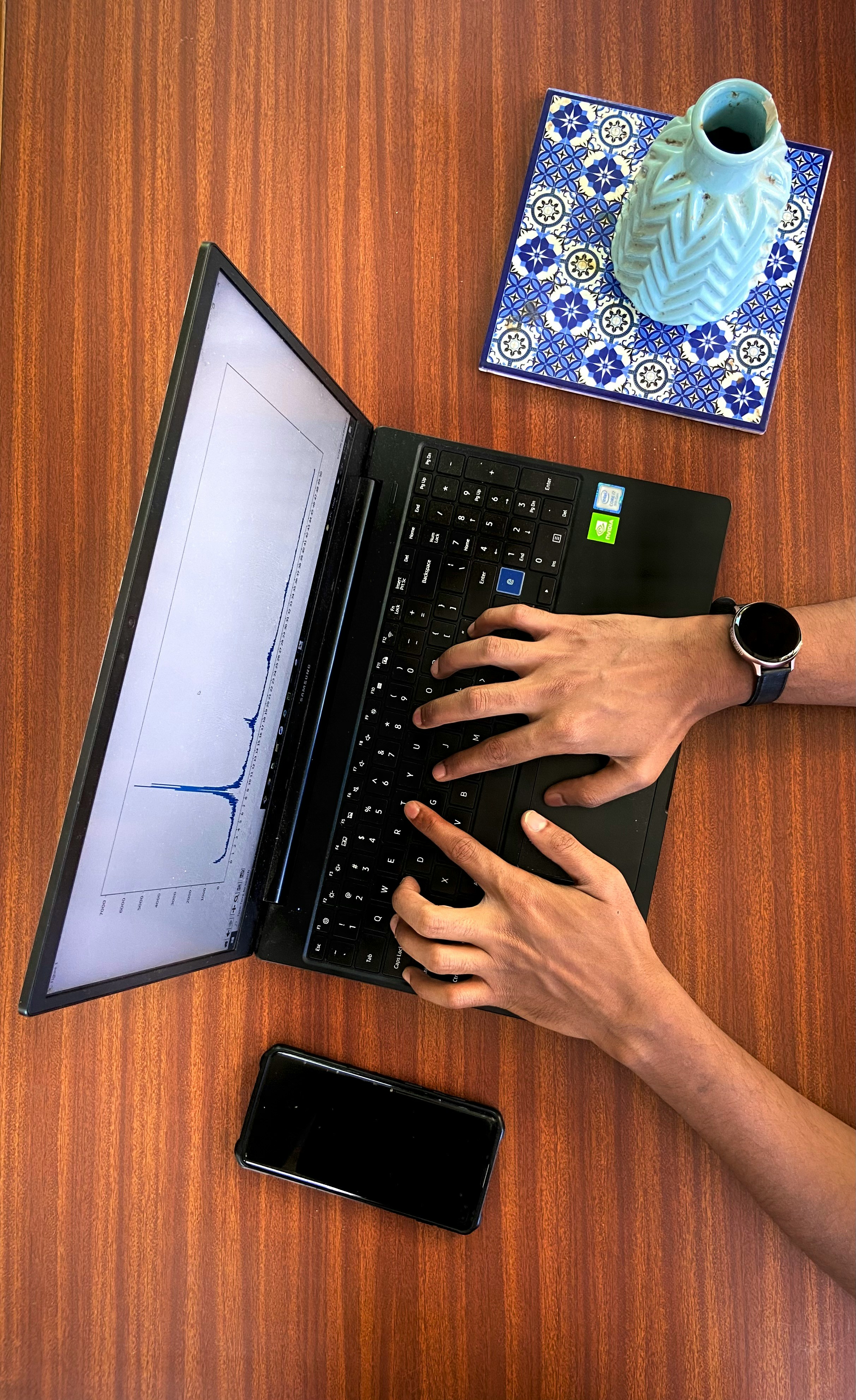 Close up of hands typing on a laptop with financial data graphs on screen