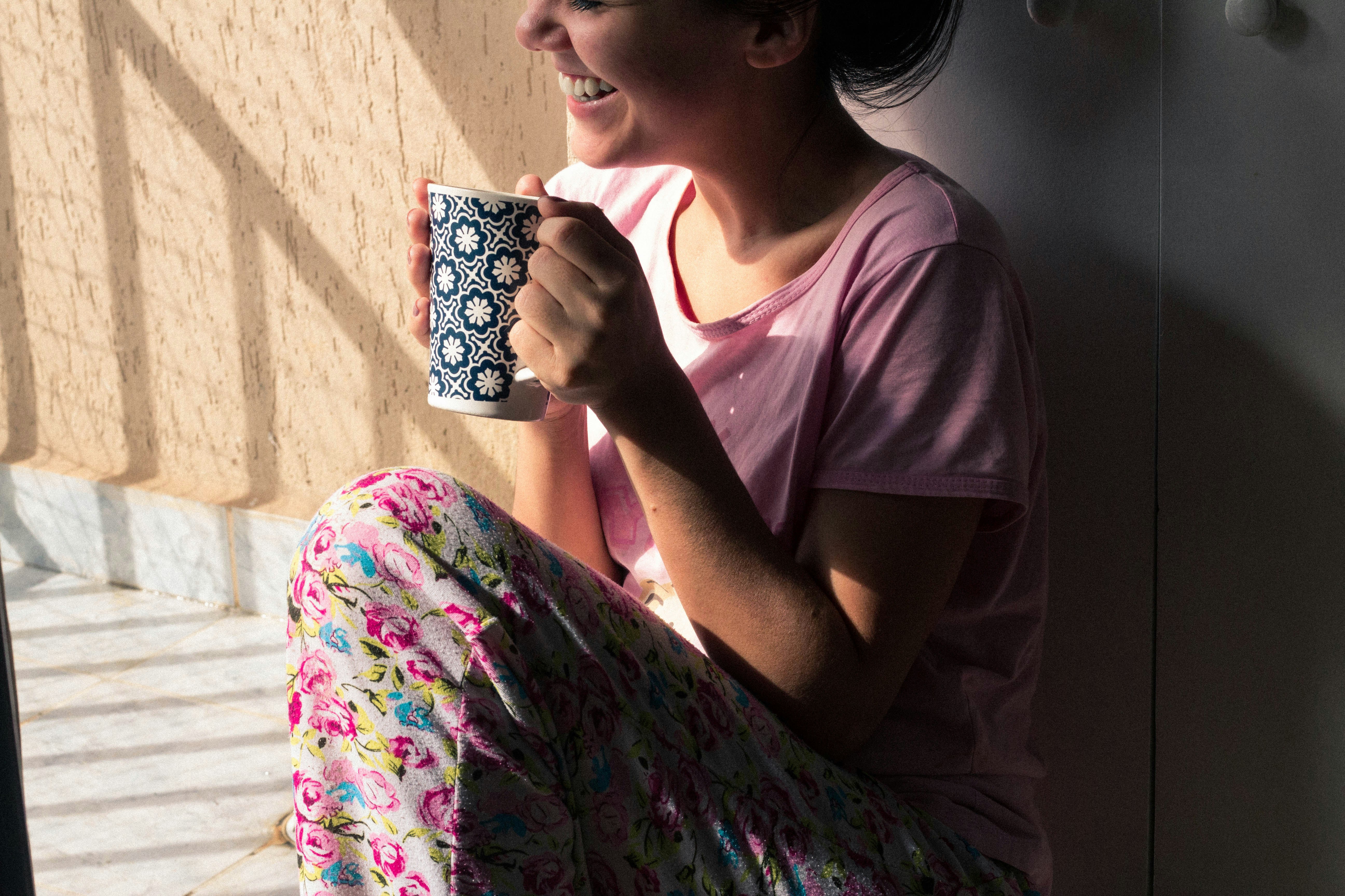 Young woman sitting in a cozy armchair holding a cup of tea, looking serene and hopeful