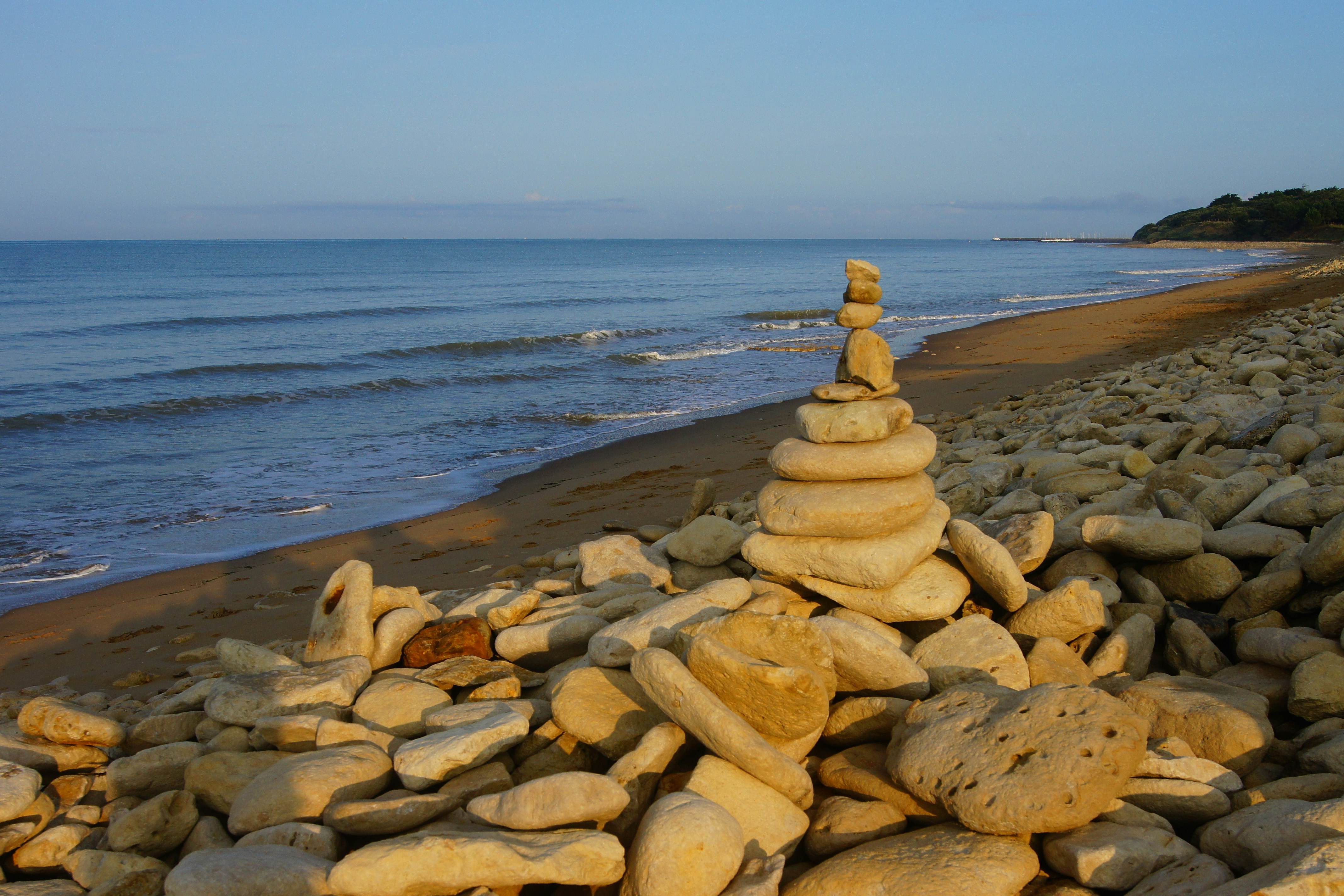 Unsplash image showing stones balanced on a tranquil beach representing chakra alignment
