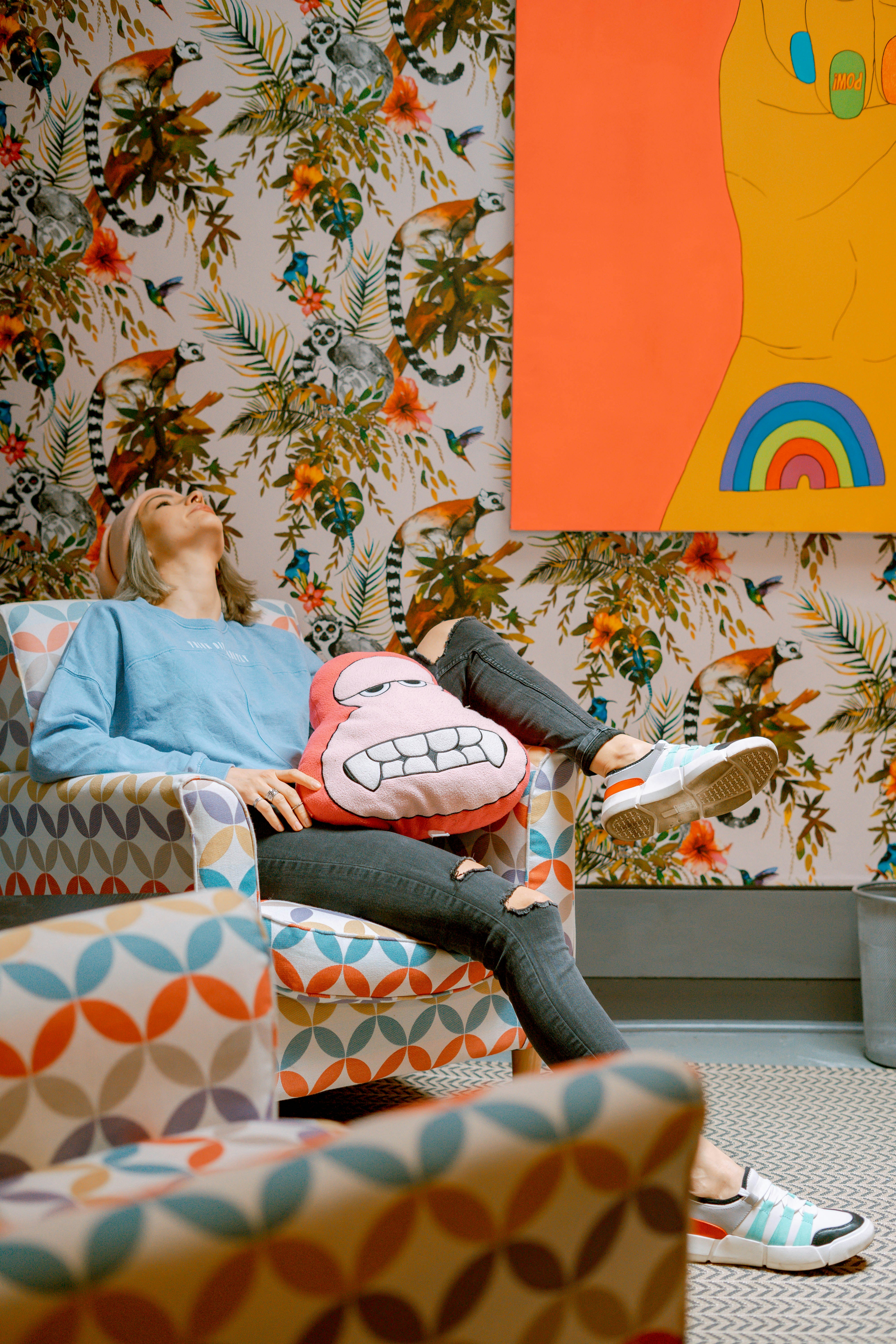 Happy woman relaxing on sofa in front of a geometric colorful wall