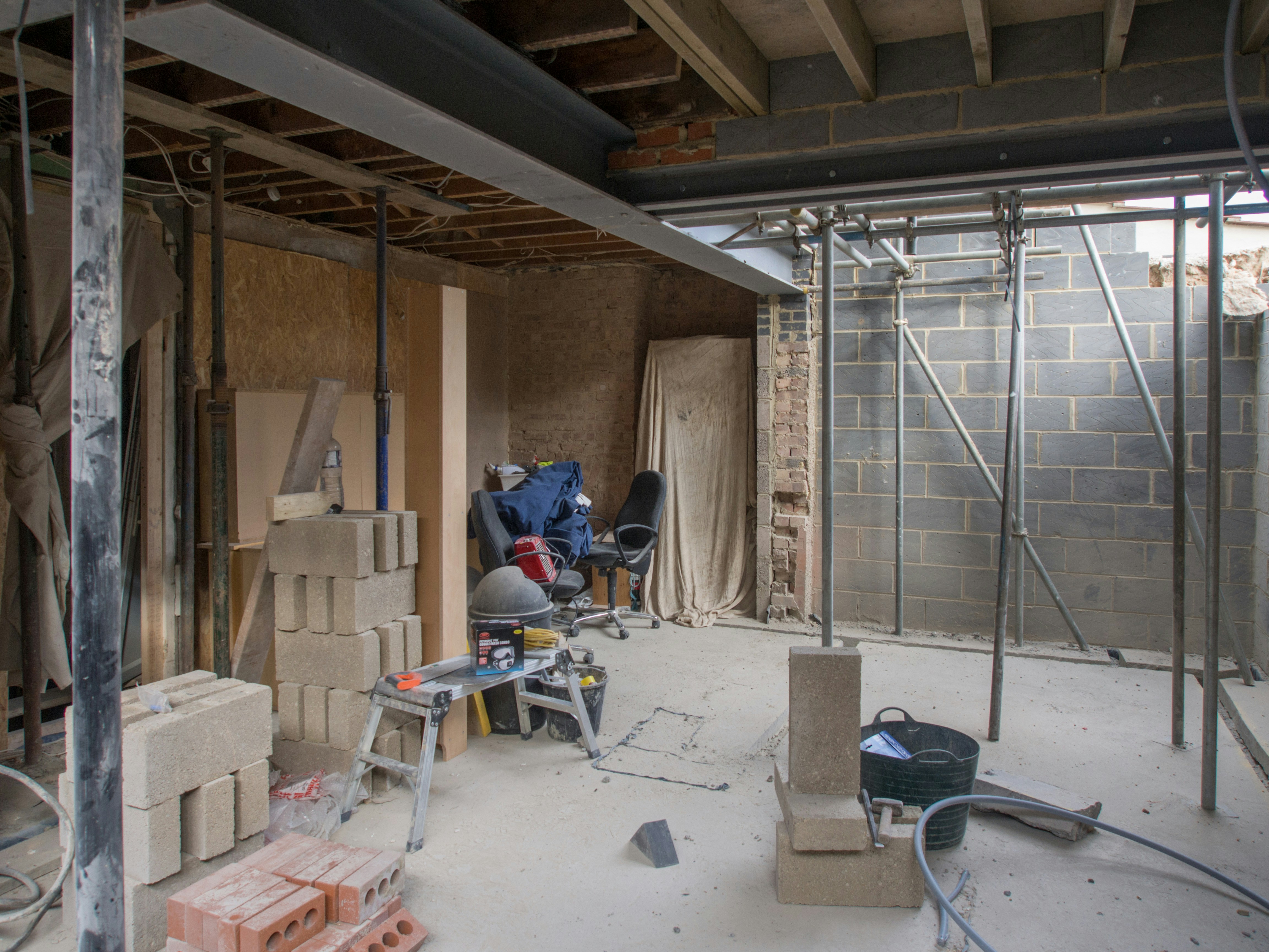 Workers applying plaster on a wall during a home renovation process, showing tools and materials.