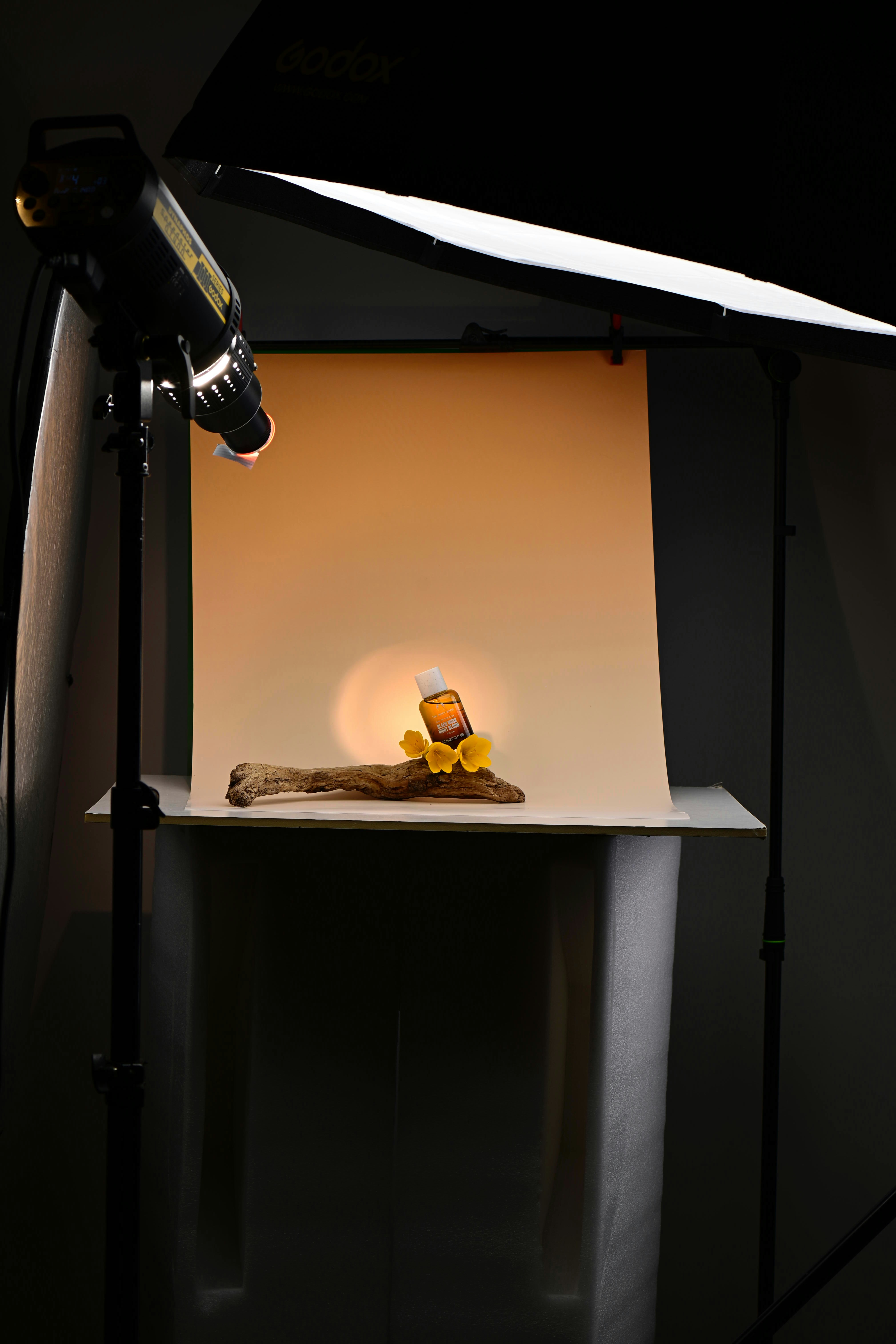 Backstage view of a photography studio showing lighting setup, beanbag and photographer gently positioning a baby doll for practice