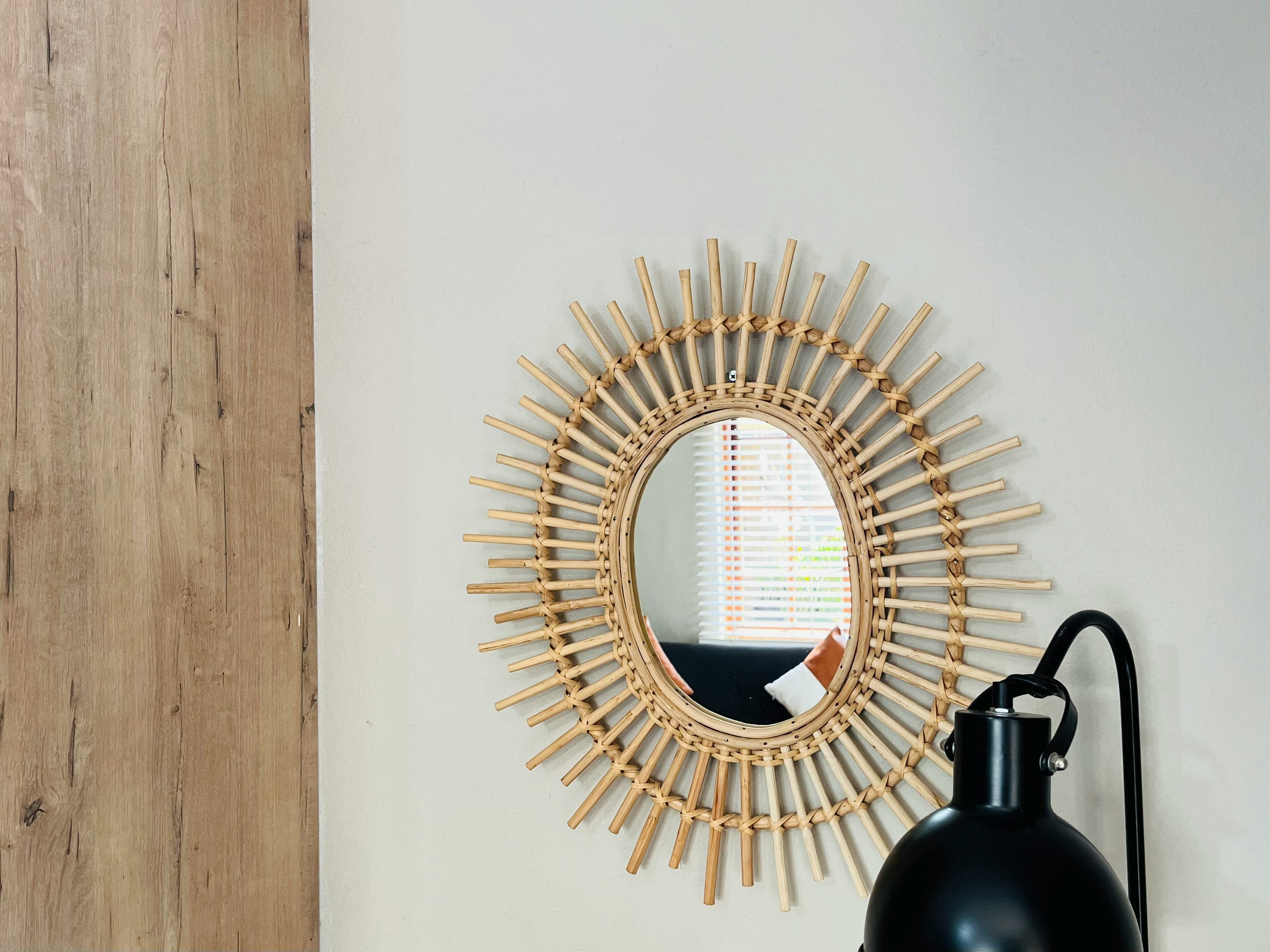 Asymmetrical modern mirror hanging on a textured wall reflecting natural light