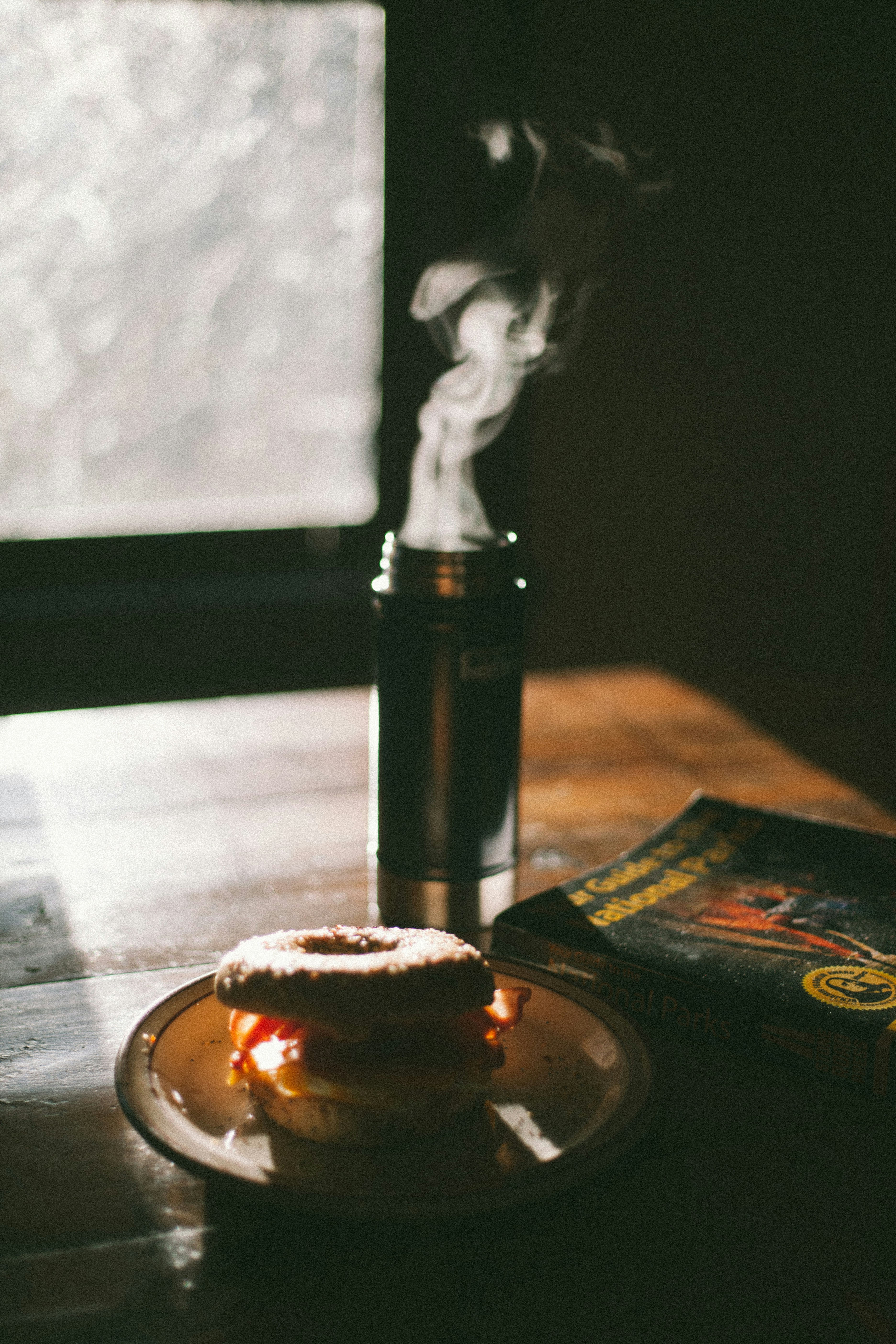 Close up of burning white sage stick with smoke and crystals on a wooden table