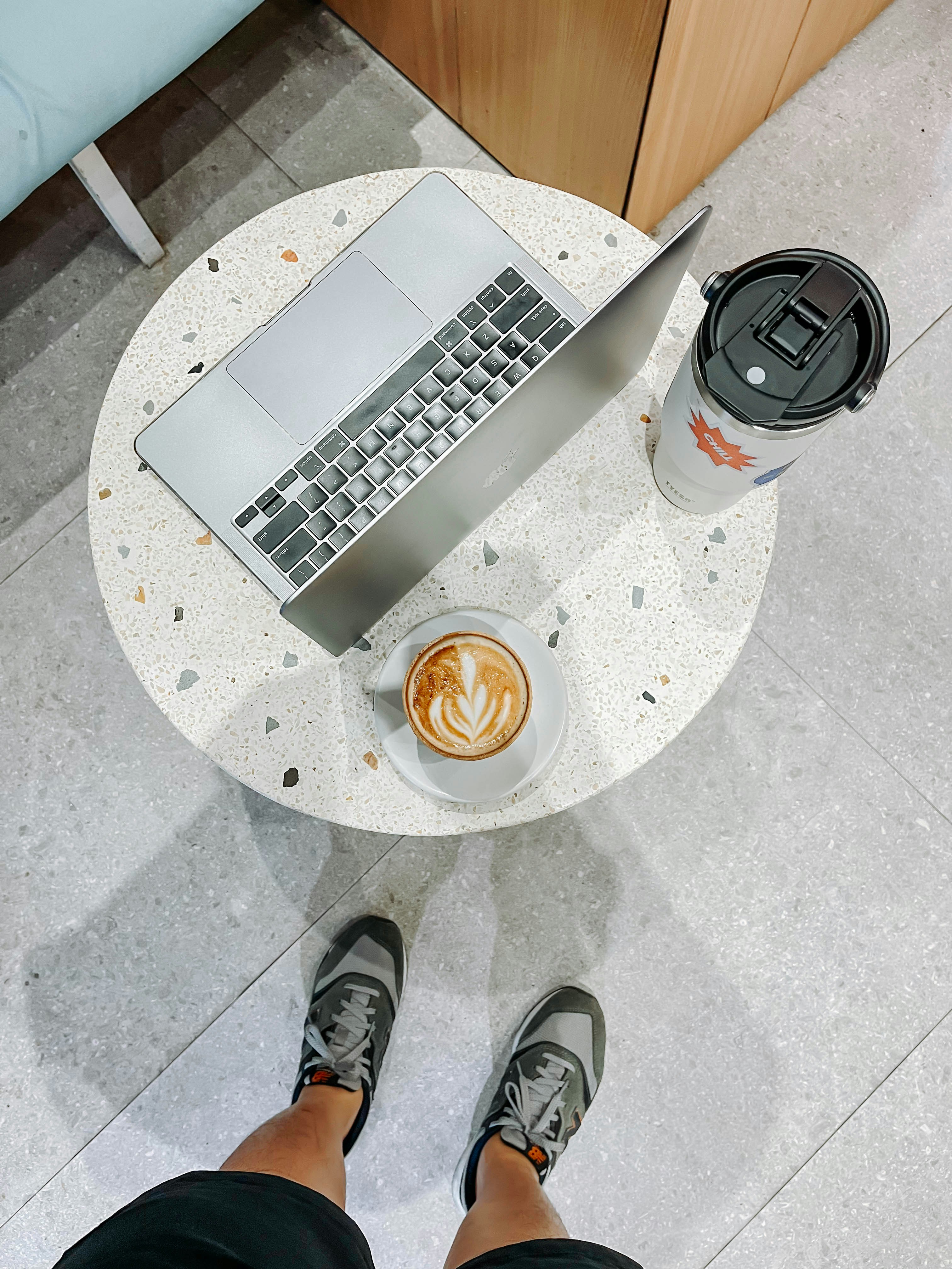 A programmer typing detailed code on a laptop screen with coffee on the desk