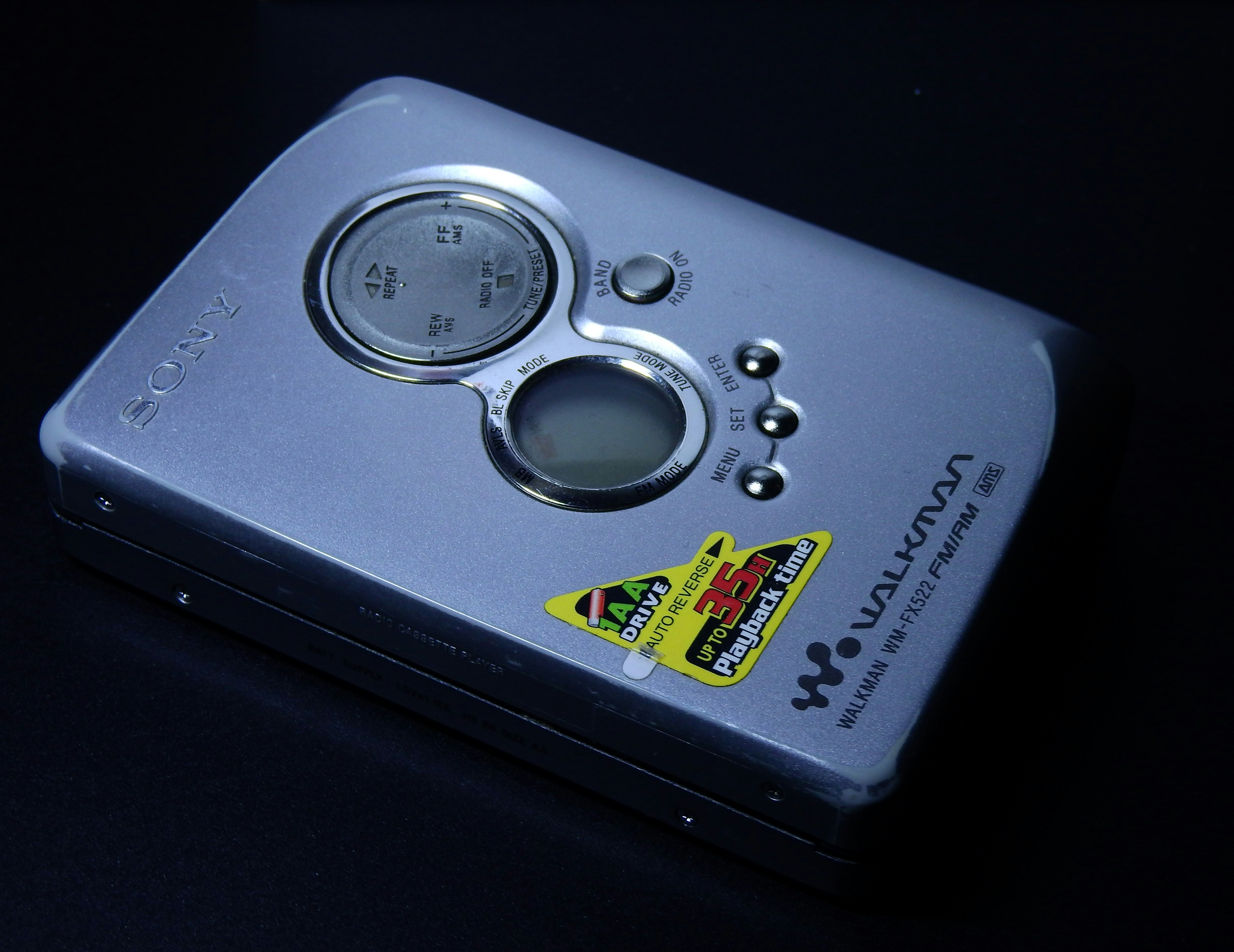 Close up of a modern mirrorless camera dial set to Manual mode with a blurred cityscape background