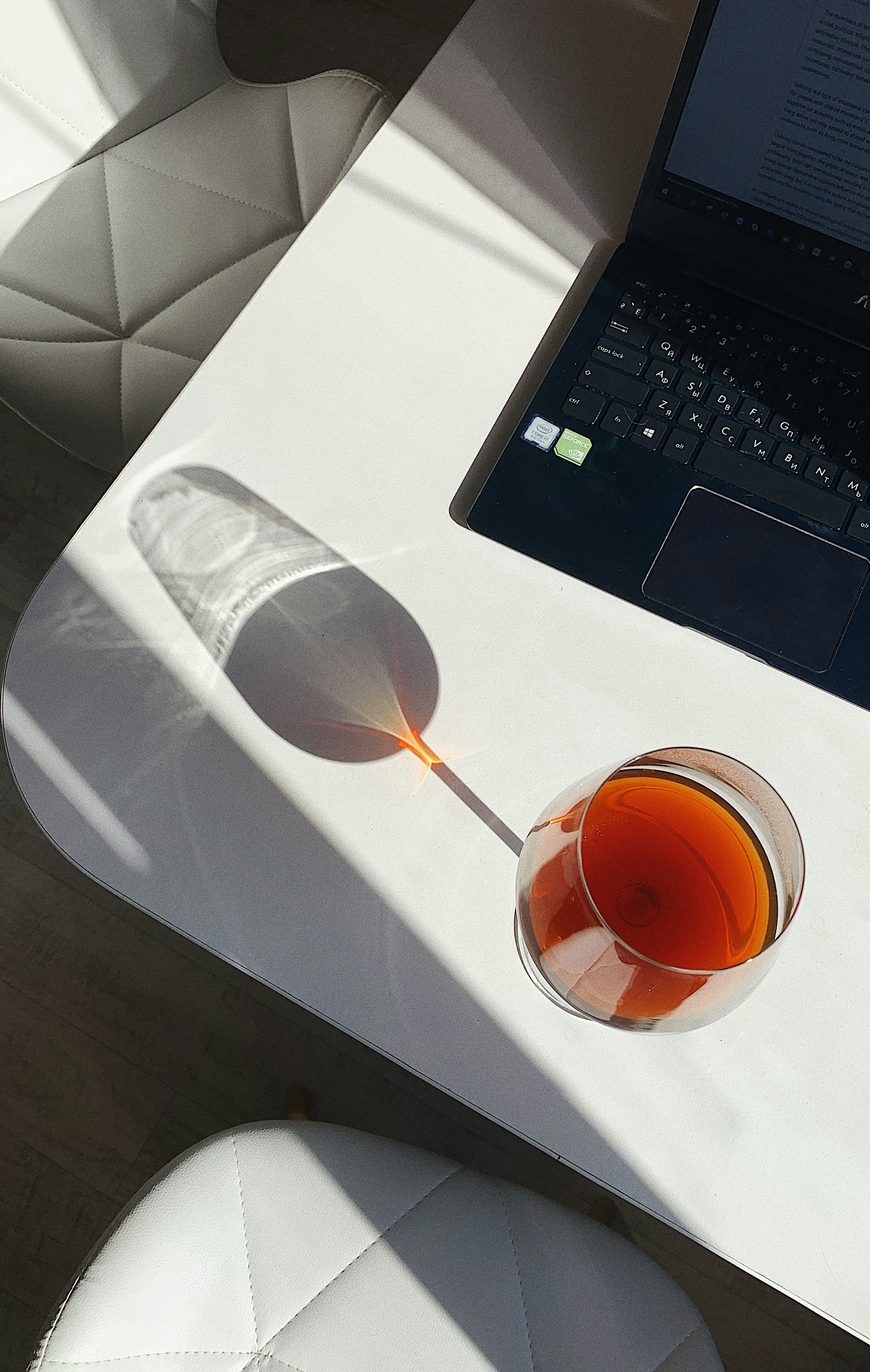 Close up of a person typing on a laptop with a coffee cup nearby in a bright home office setting