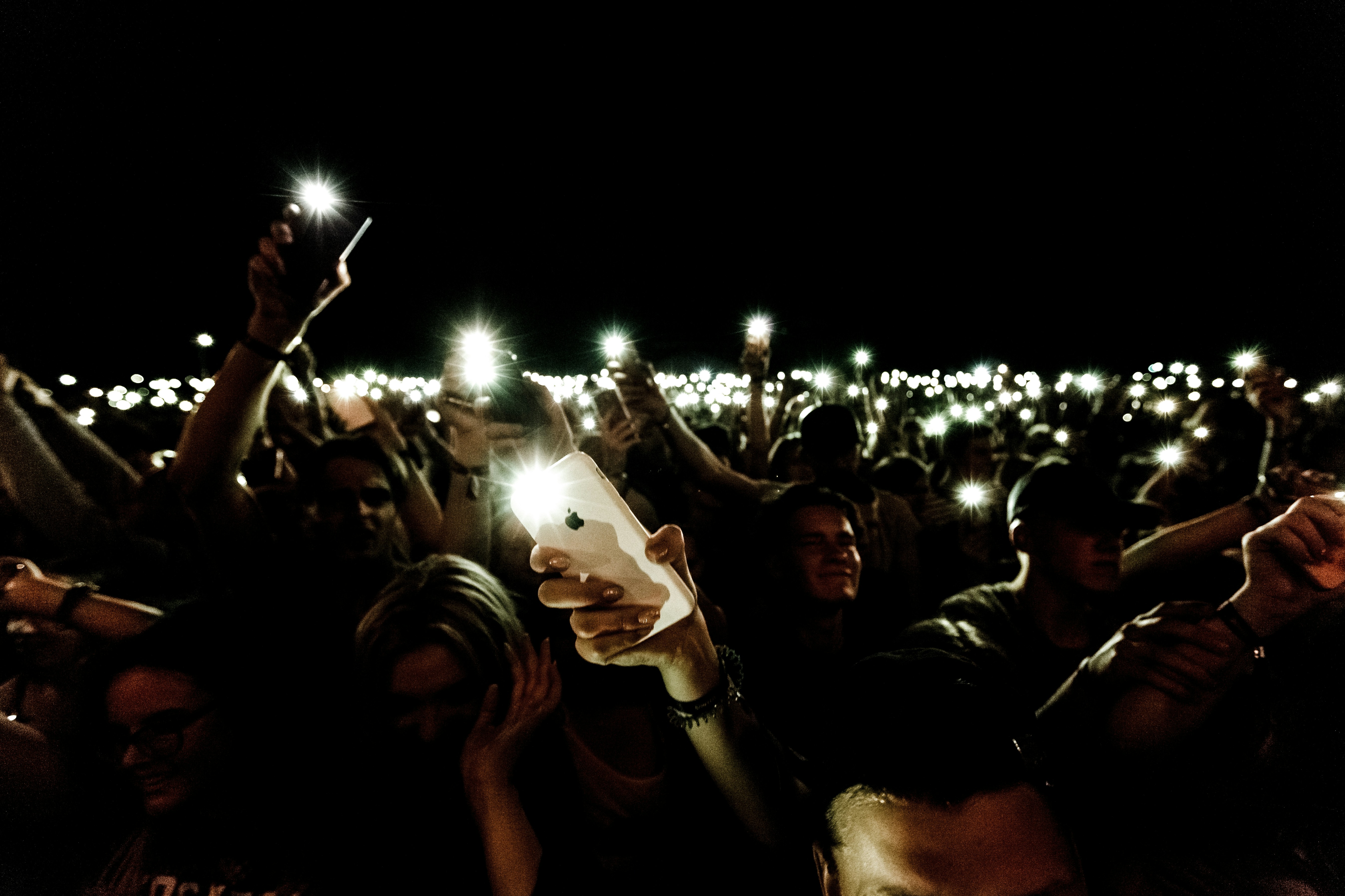 A blurred background image of a concert crowd waiting for a show to start, many holding smartphones