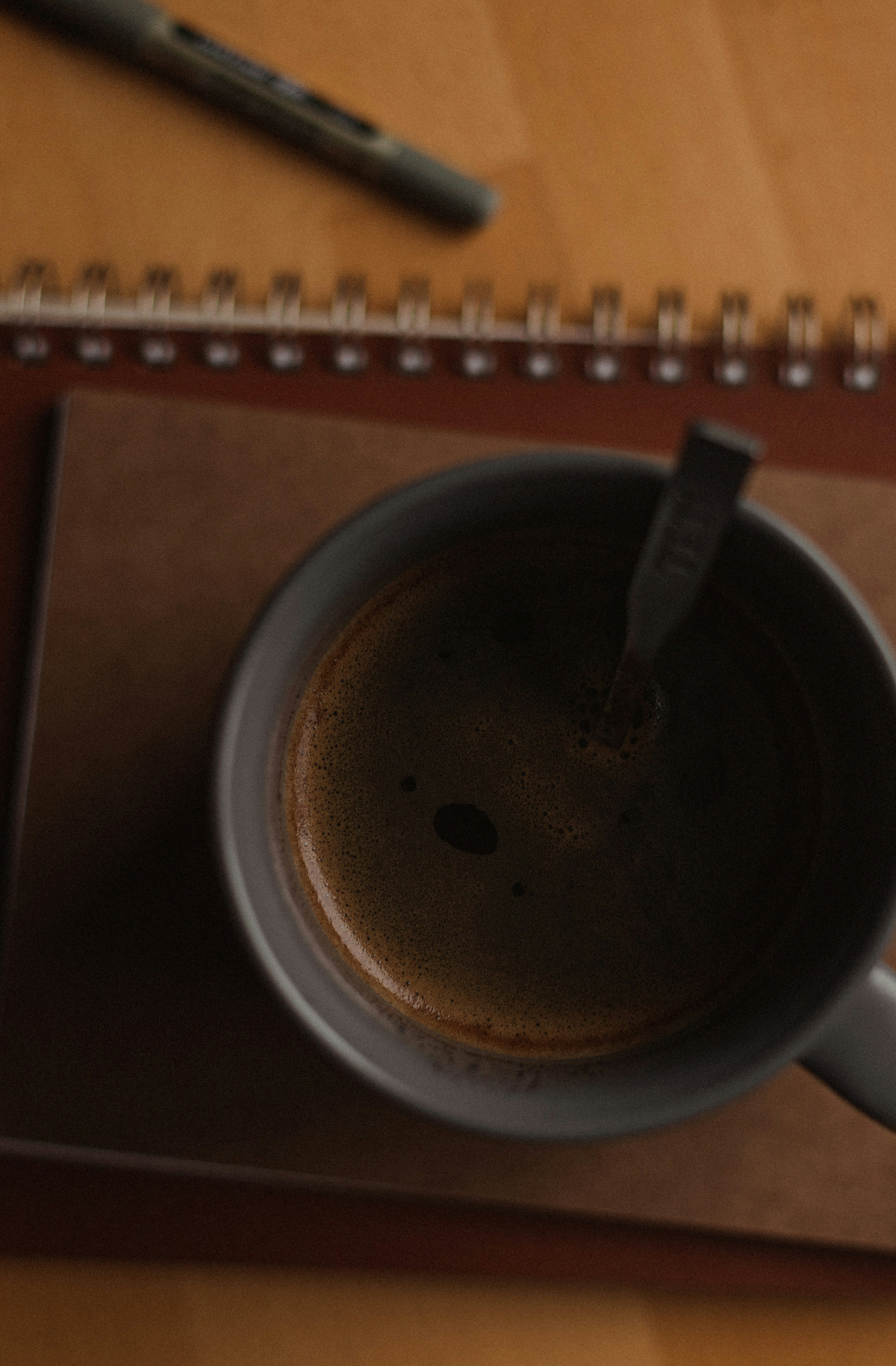 Close up of a hand writing on a notebook with a calculator and coffee on a wooden table