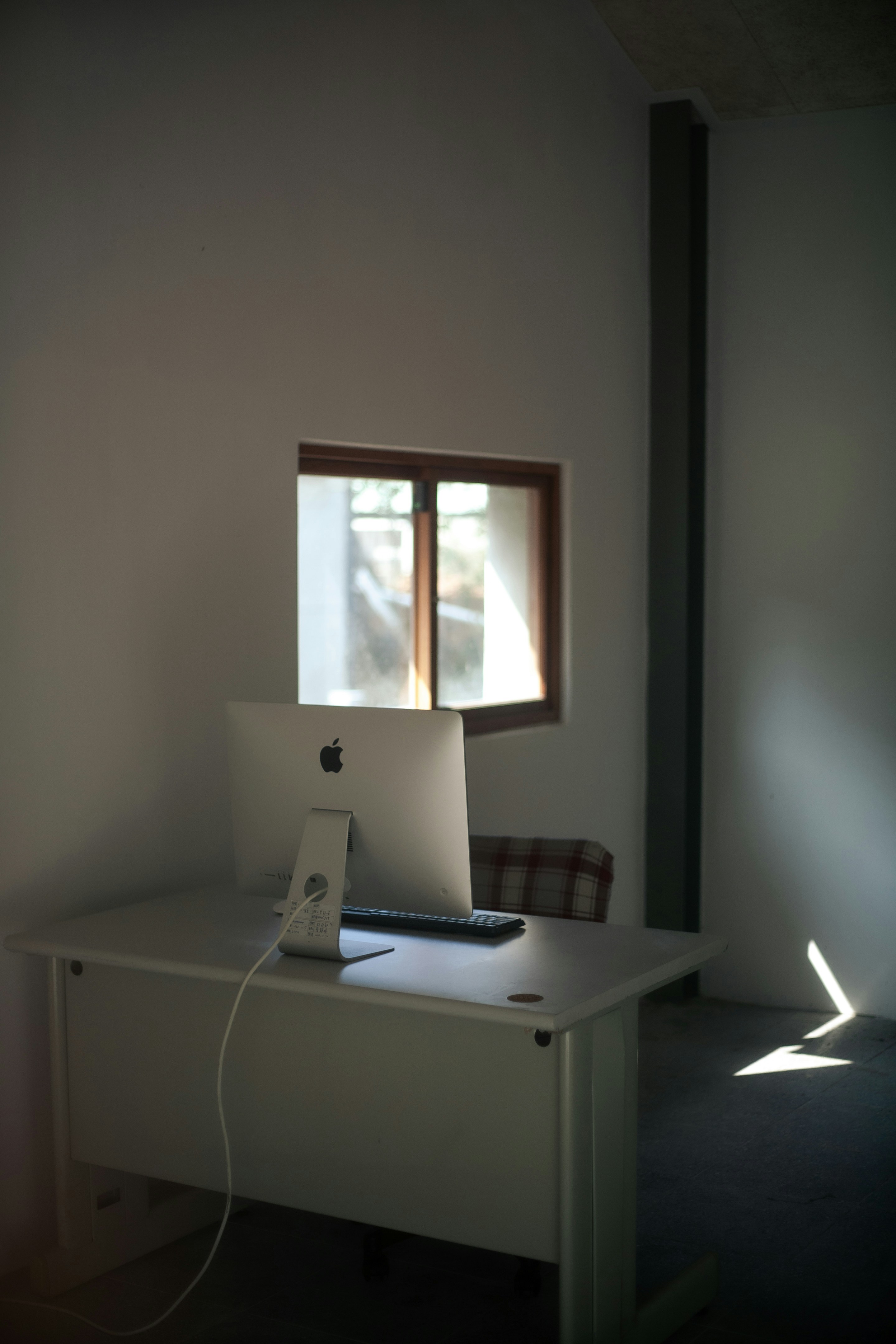 Minimalist corner desk setup in a small apartment utilizing natural light