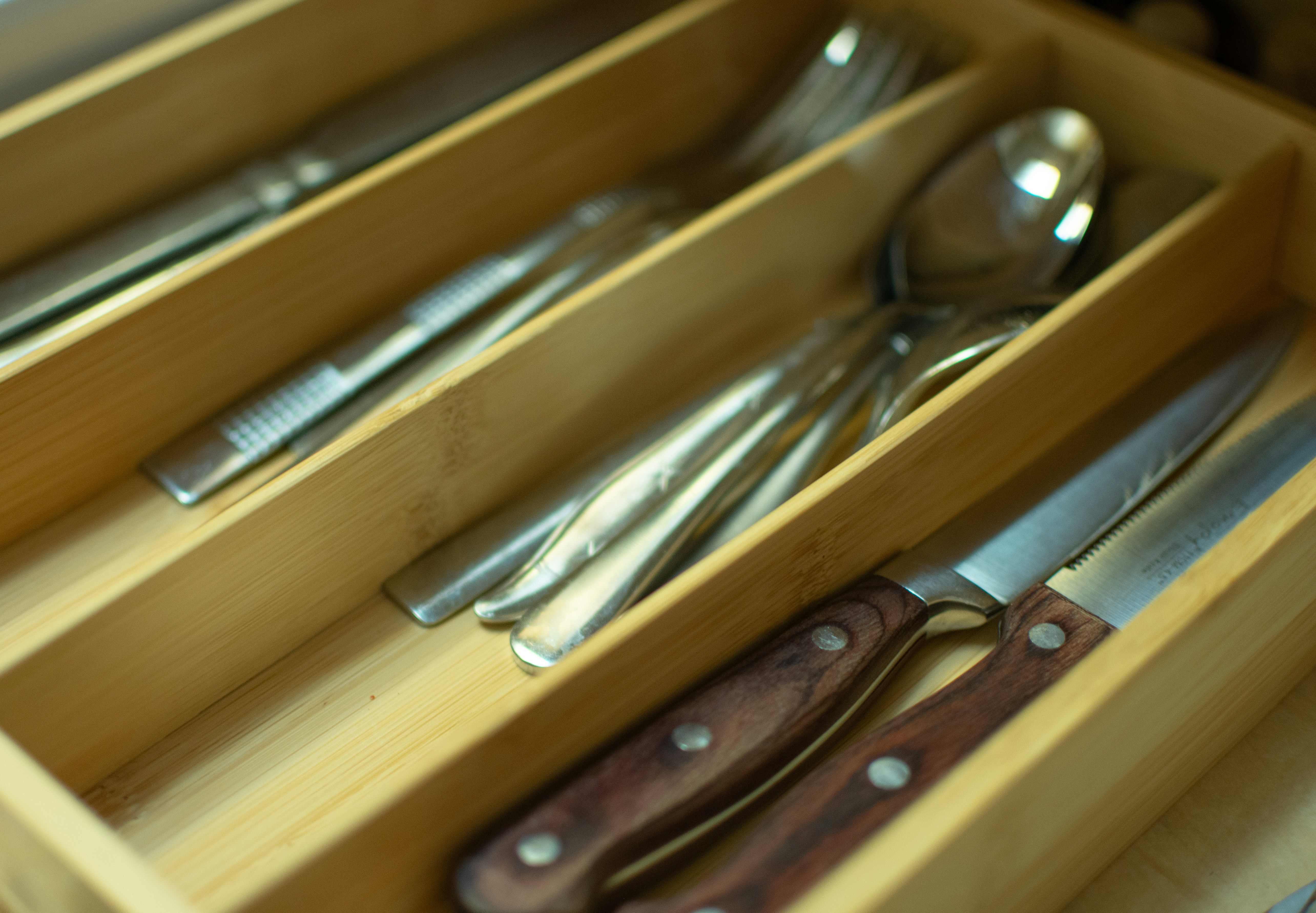 Inside of a drawer perfectly organized with dividers for cutlery and small kitchen tools