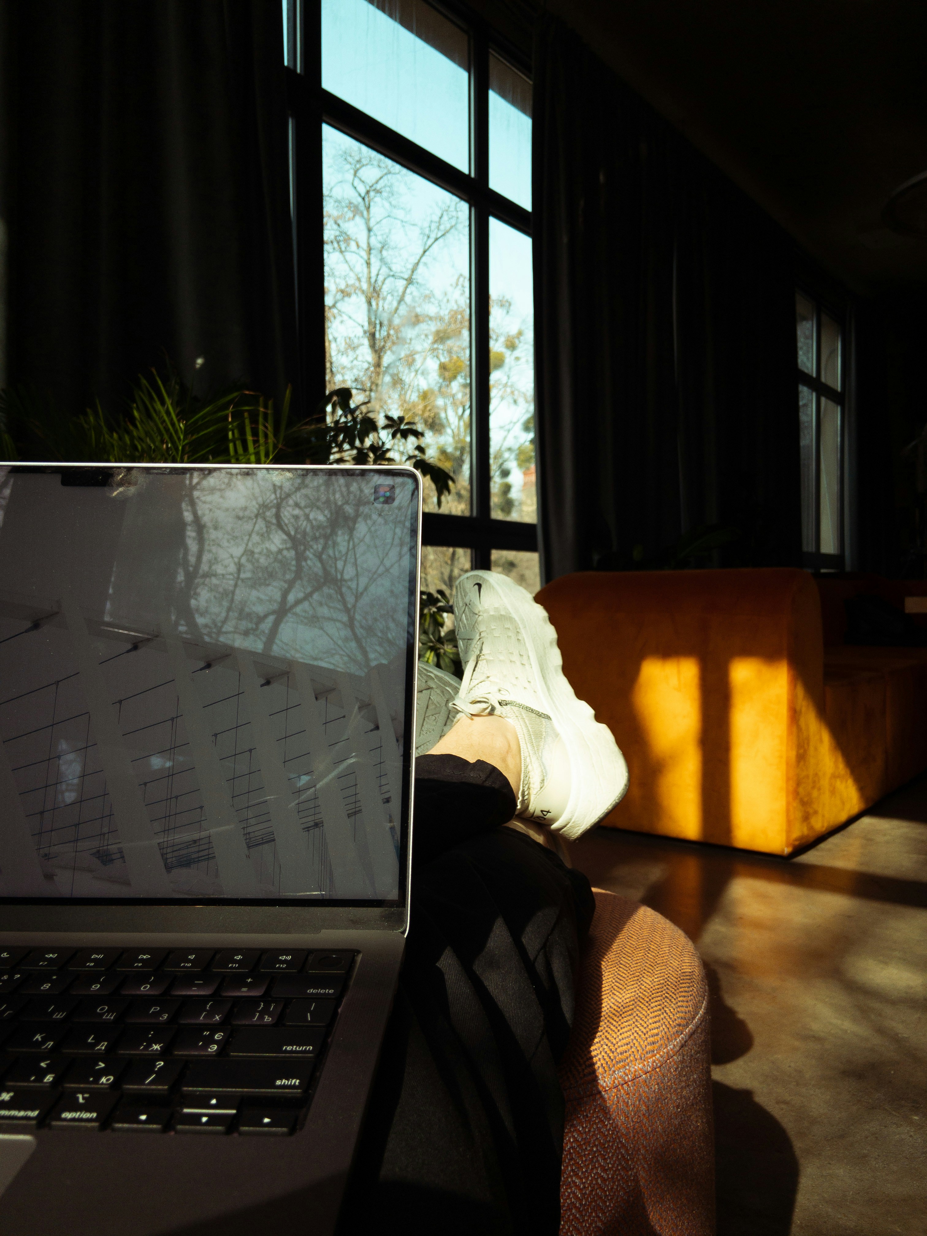 woman sitting on yoga mat in living room looking at laptop screen following instructions from therapist